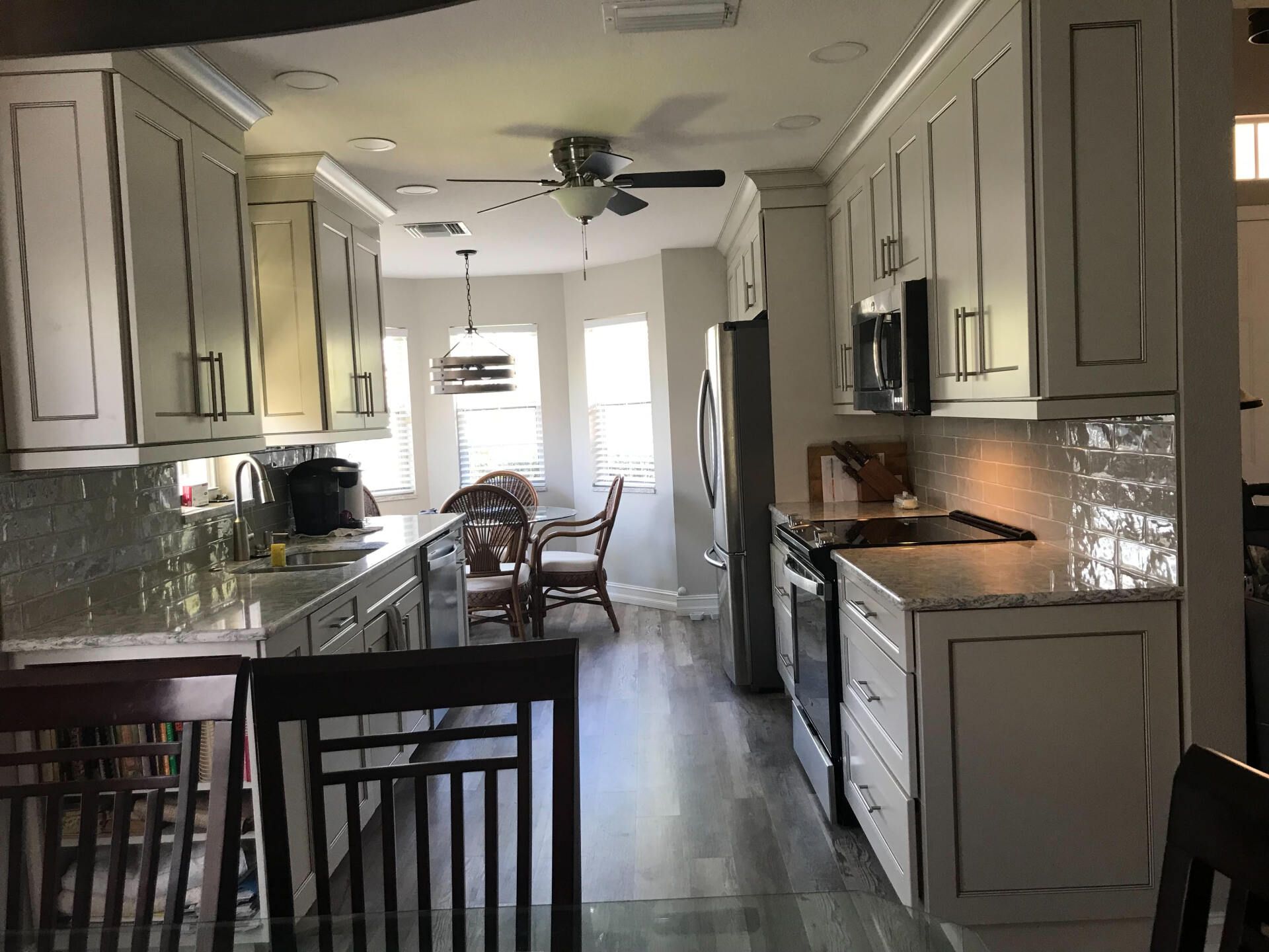 White kitchen with gray countertops, stainless steel appliances, and a dining area.