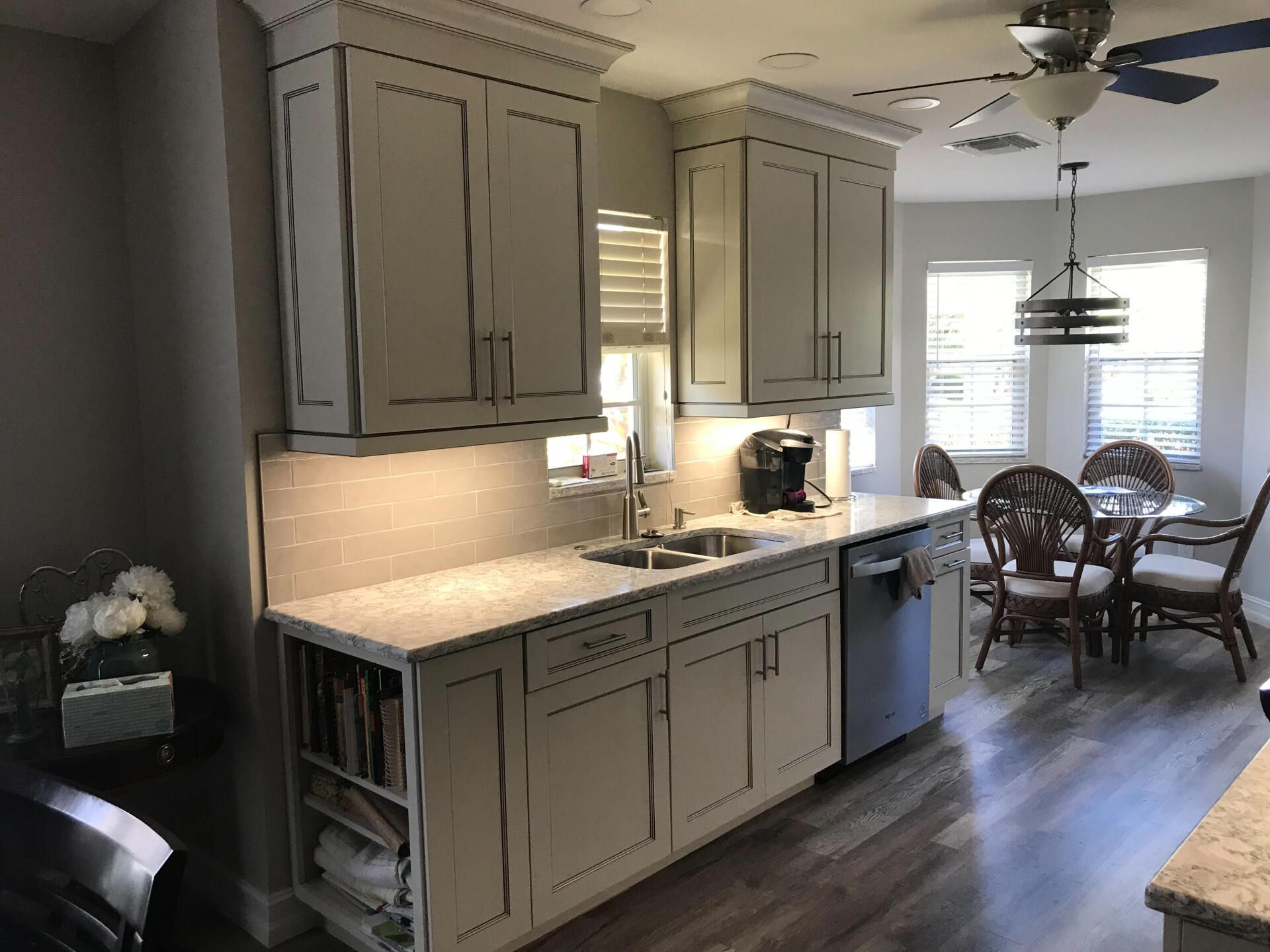 Kitchen with light gray cabinets, stainless steel appliances, and a dining area with a table and chairs.