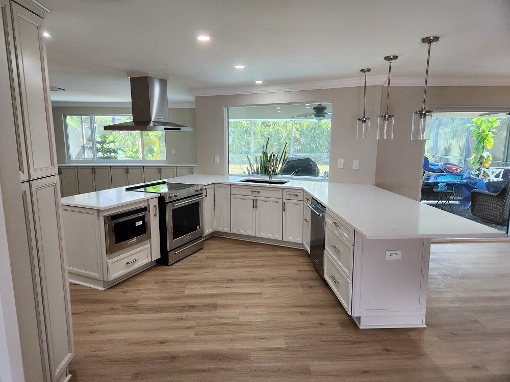 Modern kitchen with white cabinets, island, stainless steel appliances, and large windows.
