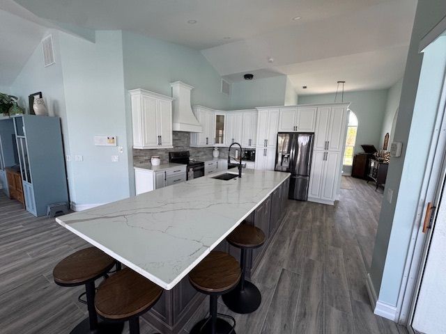 Spacious kitchen with light blue walls, large island with stools, and white cabinets.