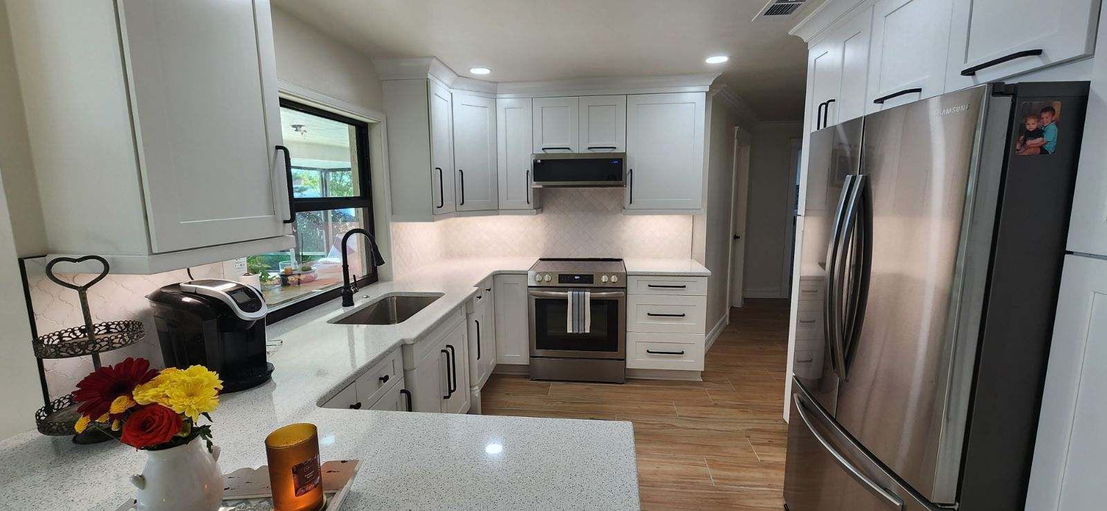 A modern kitchen with white cabinets, stainless steel appliances, and light-colored countertops.