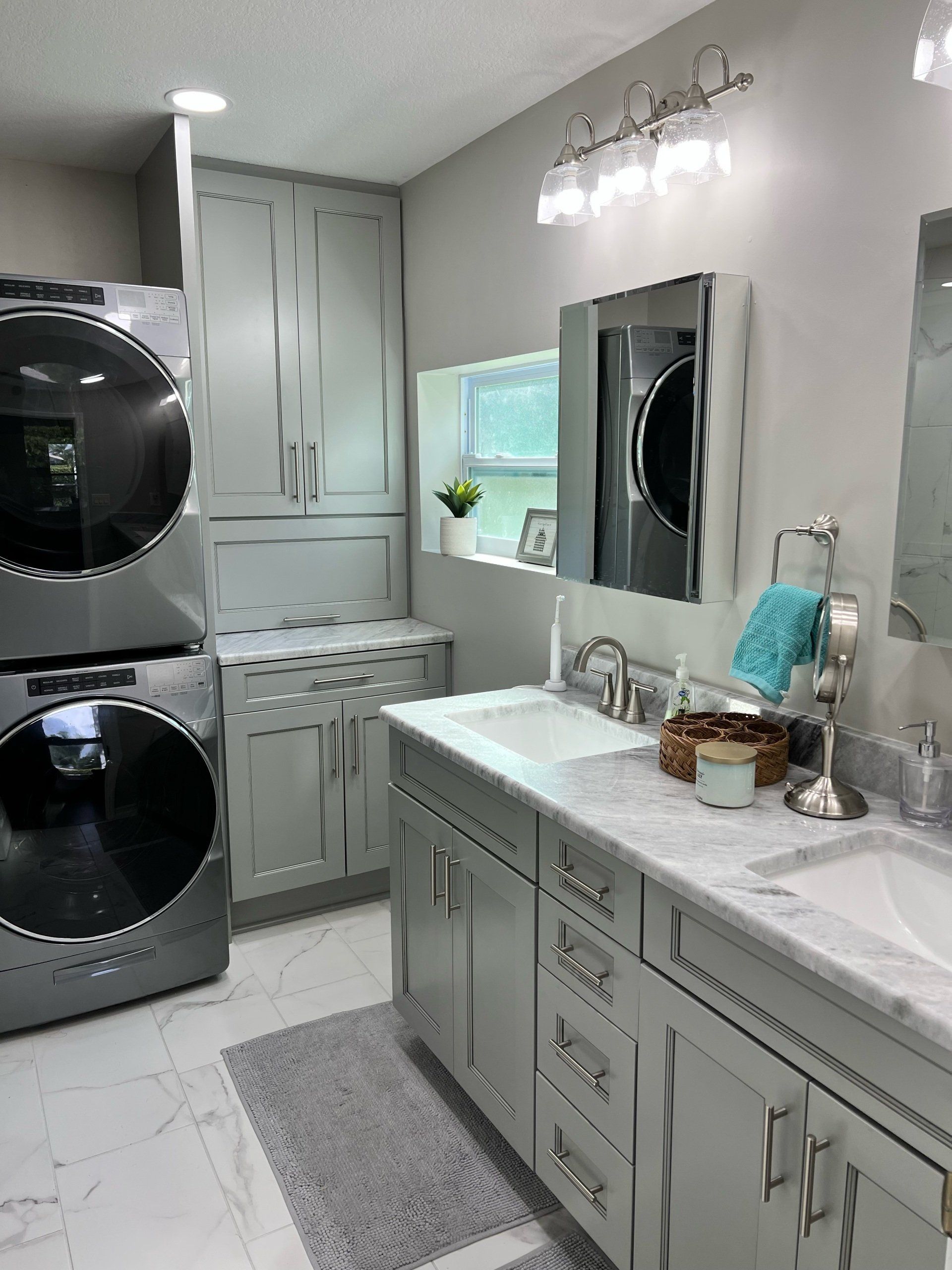 Gray bathroom with stacked washer/dryer, double vanity, and marble countertops.