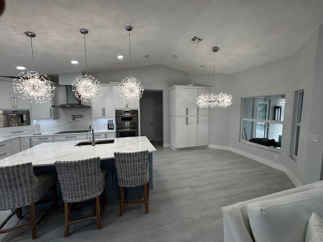 Spacious kitchen with light blue walls, large island with stools, and white cabinets.
