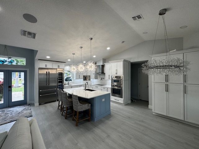 Modern kitchen with island, cabinets, and sliding glass doors to patio; wood floors, gray-blue walls.
