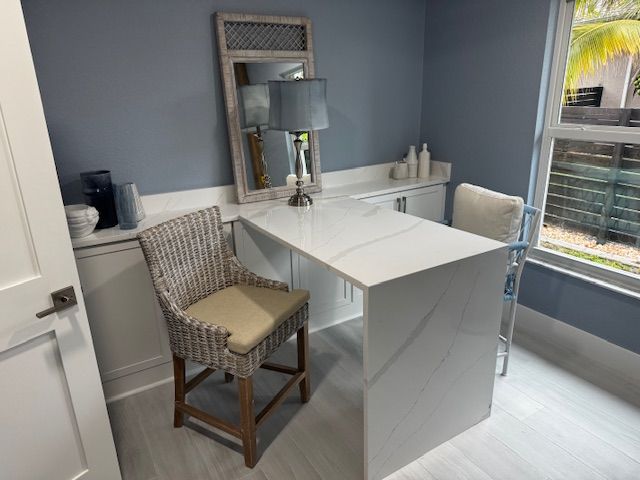 Empty, open-concept room with light wood floors, white cabinets, and a kitchen island.