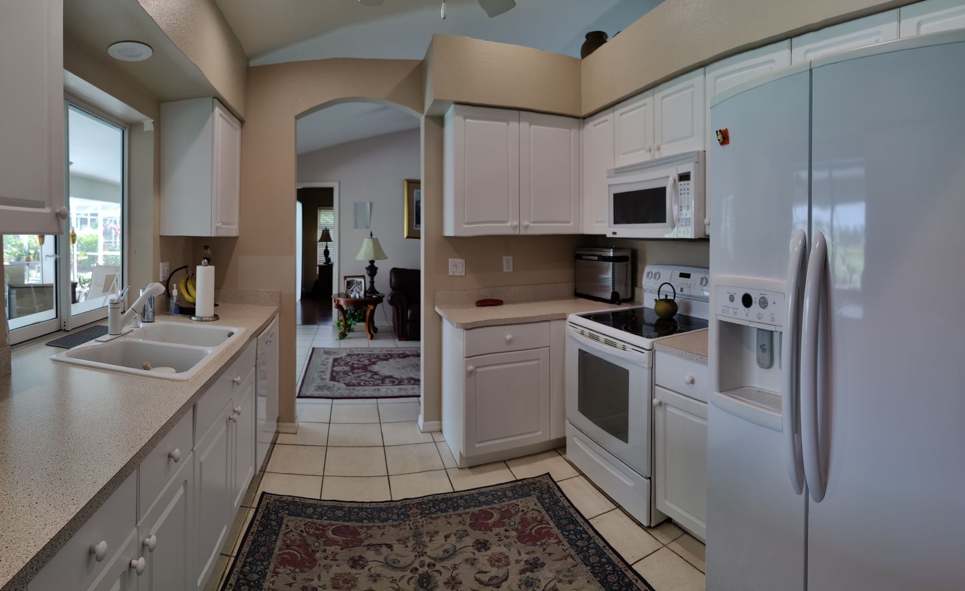 Kitchen with white cabinets, appliances, and a view into the living room.