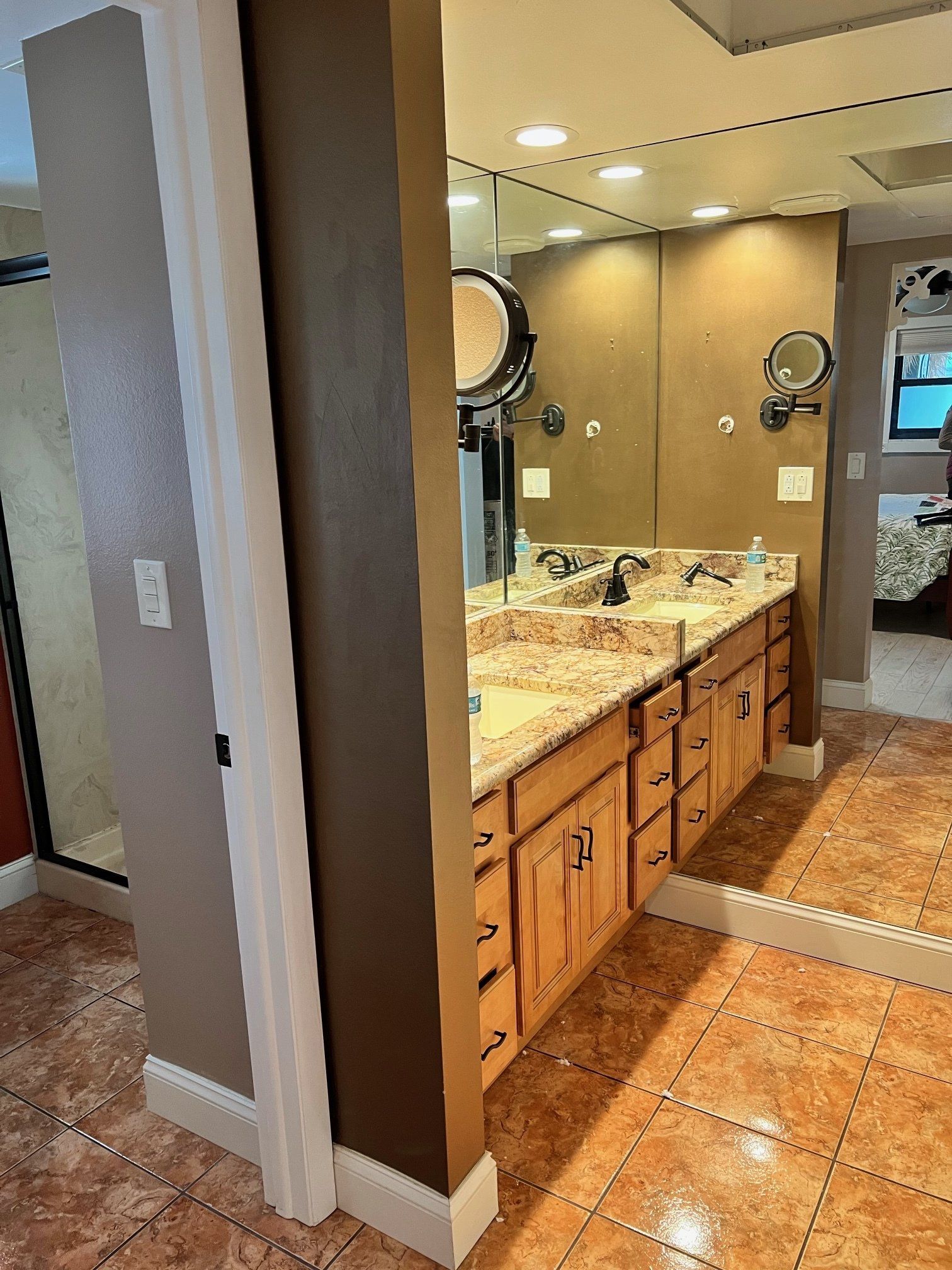 Bathroom with vanity, mirror, and tile floor. Tan cabinets and countertops, brown and white walls.
