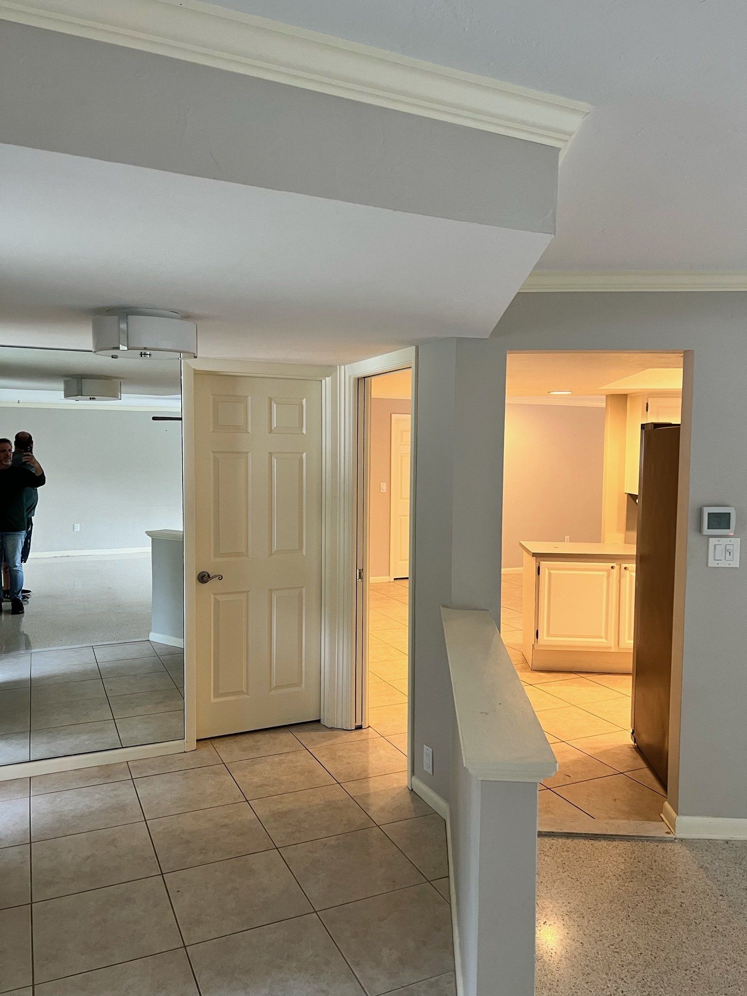 Interior view: entryway with doors leading to rooms; white walls, tile floor.