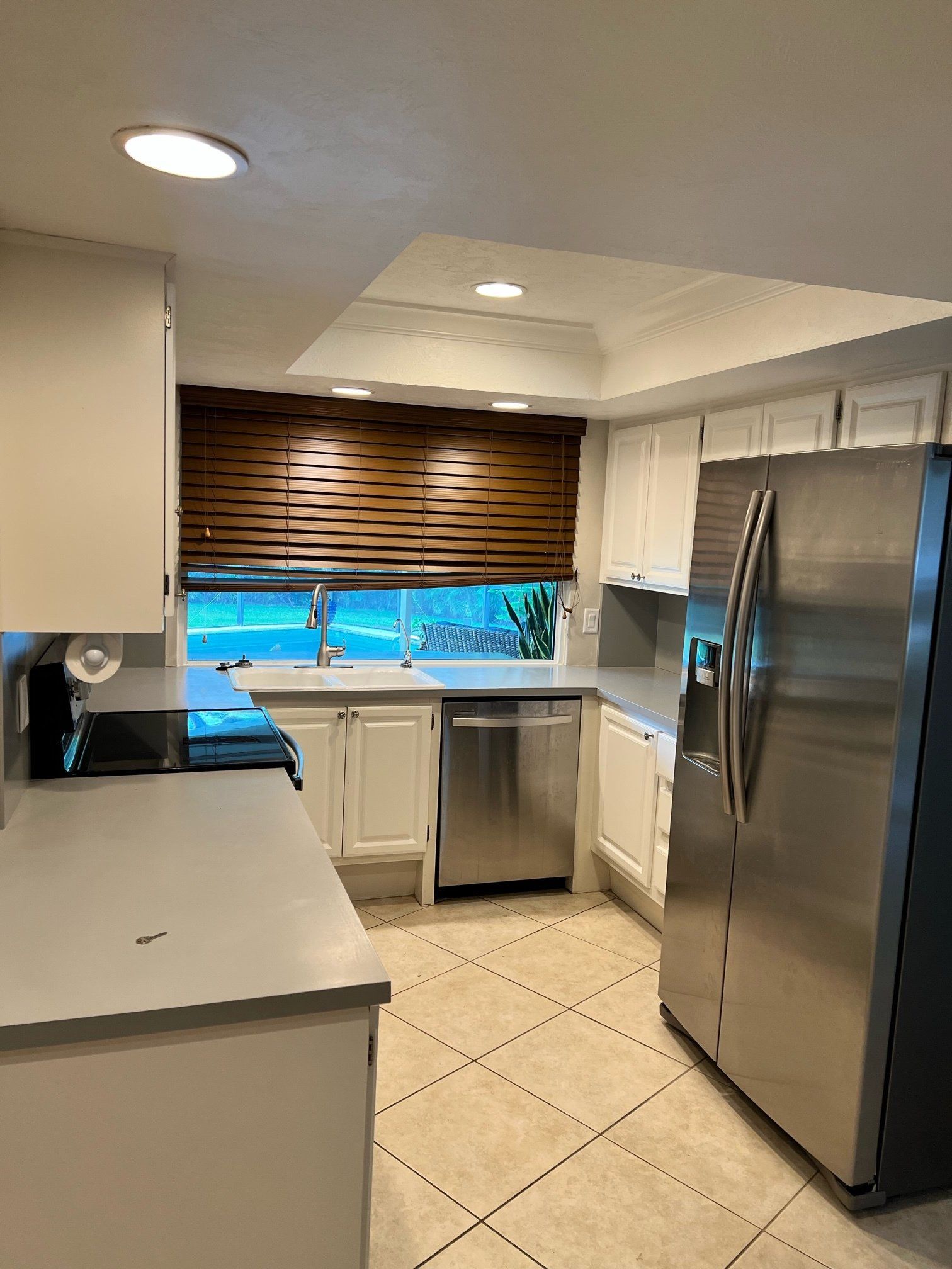 Kitchen with white cabinets, stainless steel appliances, and a wooden blind over the window.