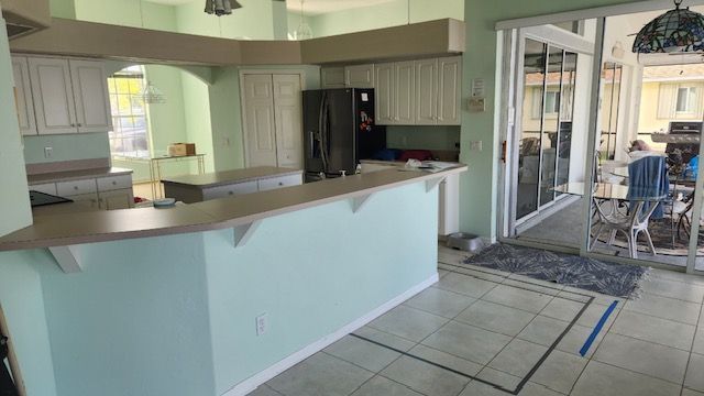 Kitchen with white cabinets, light blue walls, and a counter looking out to a patio.