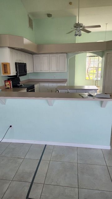 Kitchen with white cabinets, light blue walls, and a beige countertop.