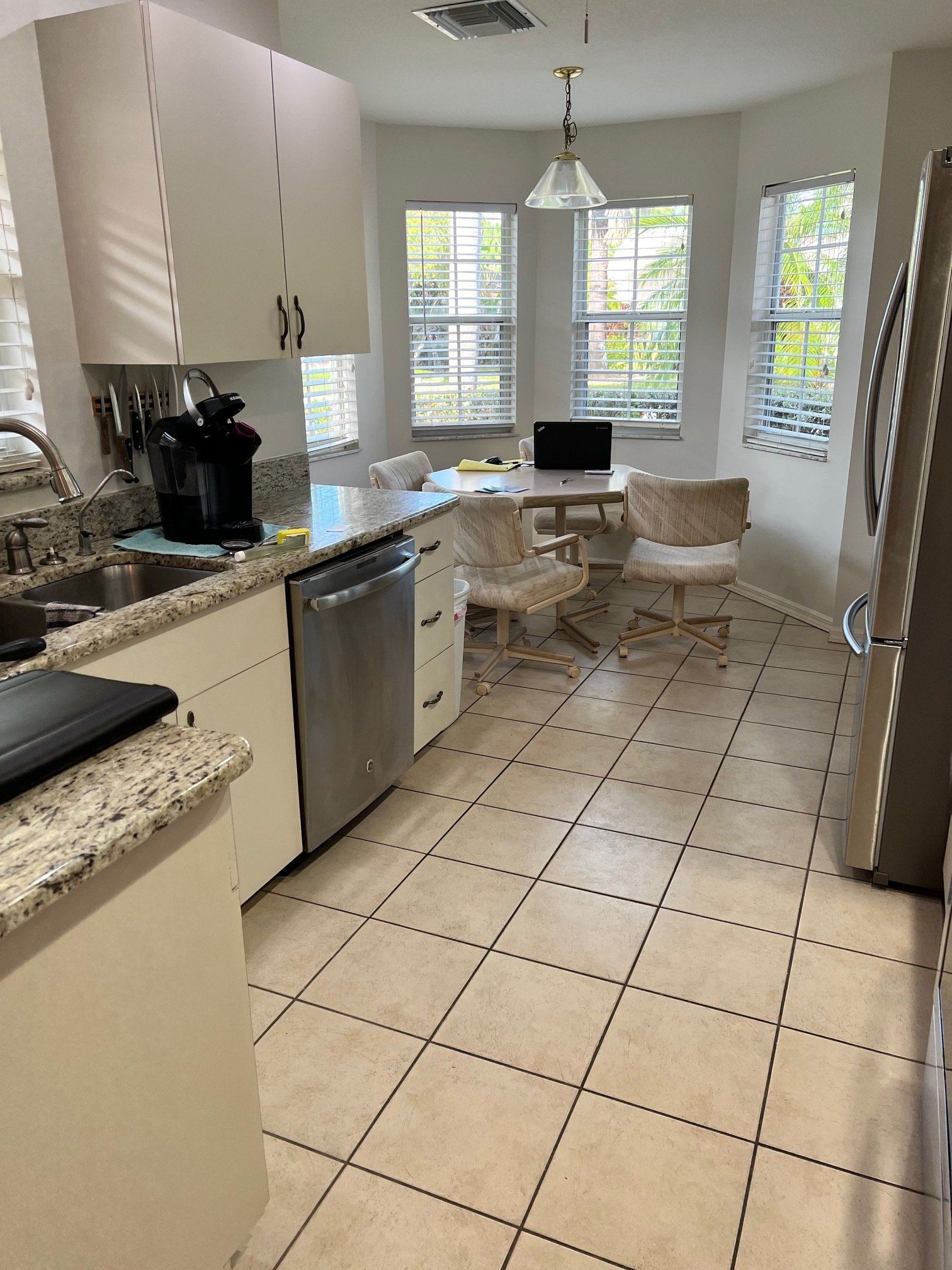 Bright kitchen with white cabinets, stainless steel appliances, and a small table near windows.