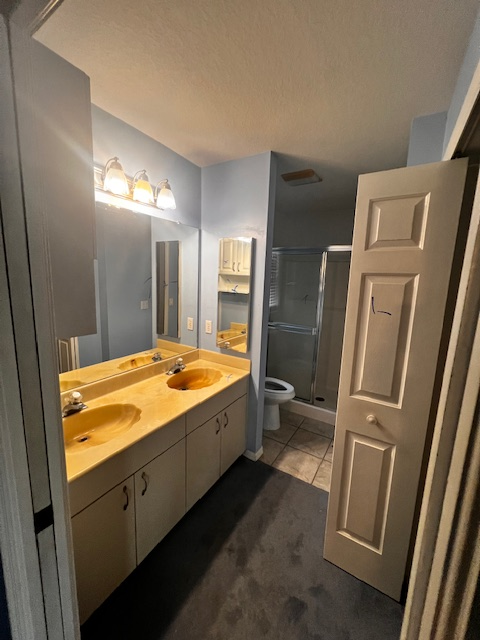 Small bathroom with white pedestal sink, toilet, dark wood floor and wall, and mirror.