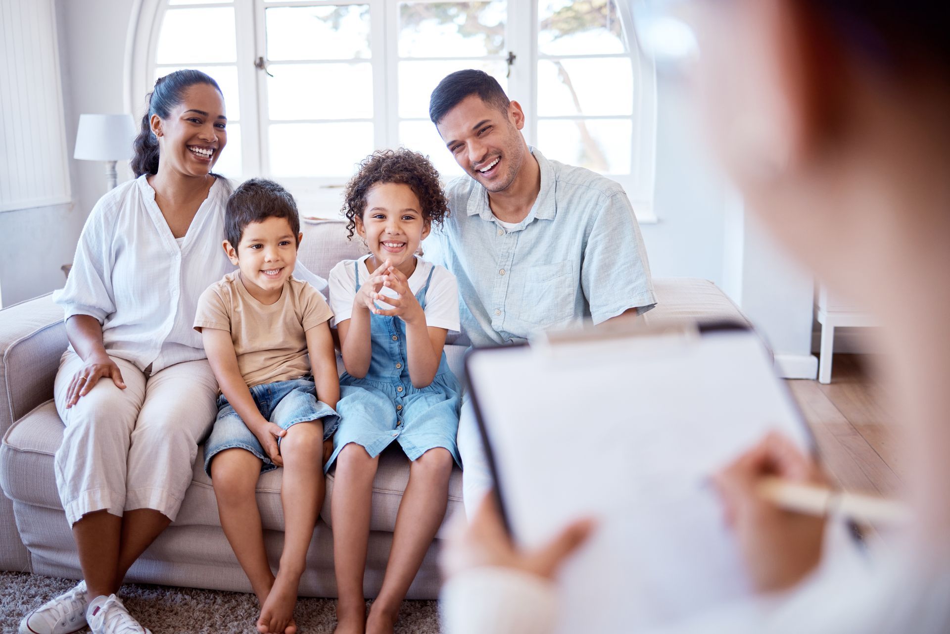 Family with two children smiling during a consultation, someone is taking notes.