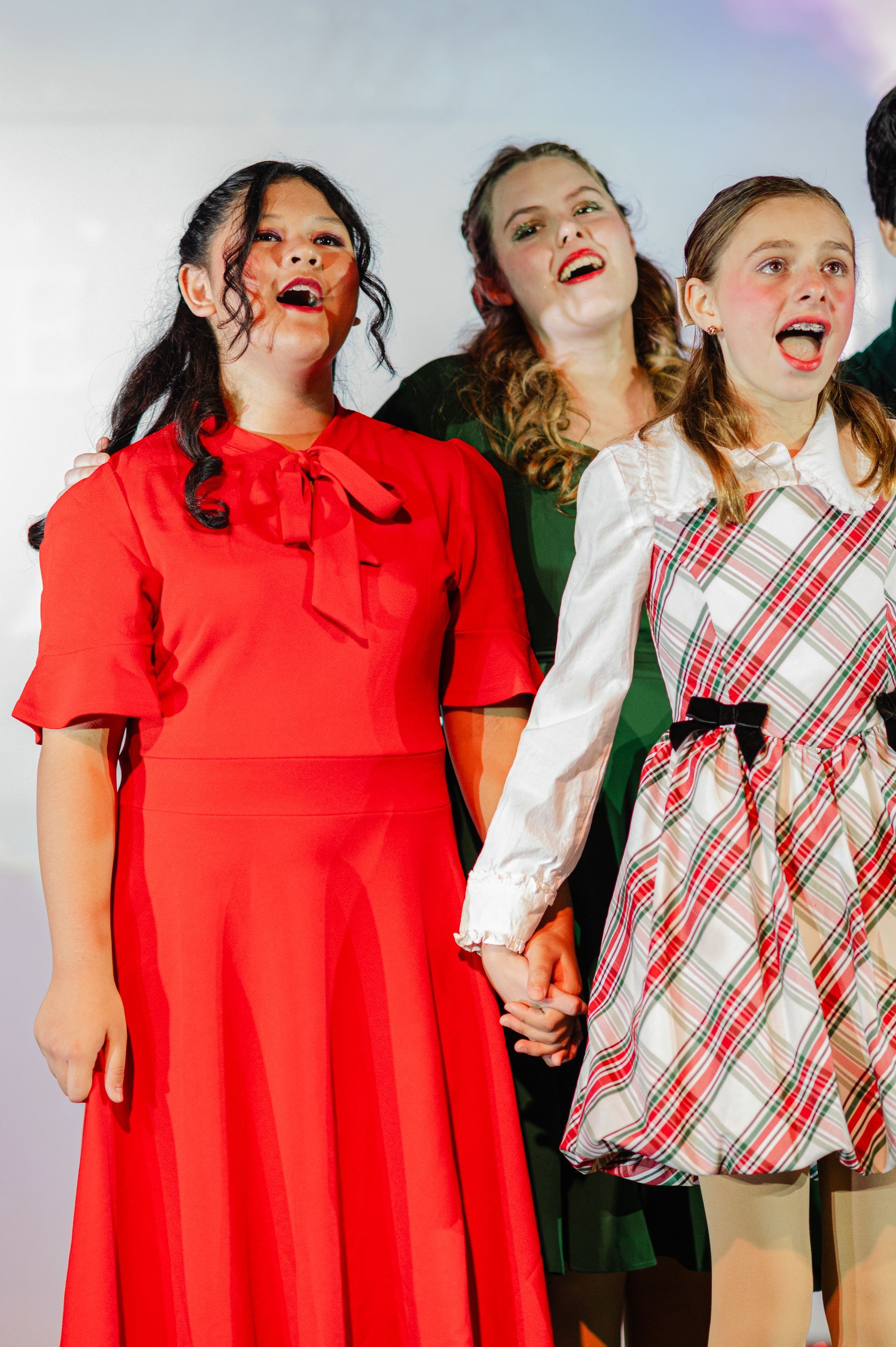 Children's Musical Theatre South Bay California Kids Theater sing onstage, smiling with microphones against a white backdrop.