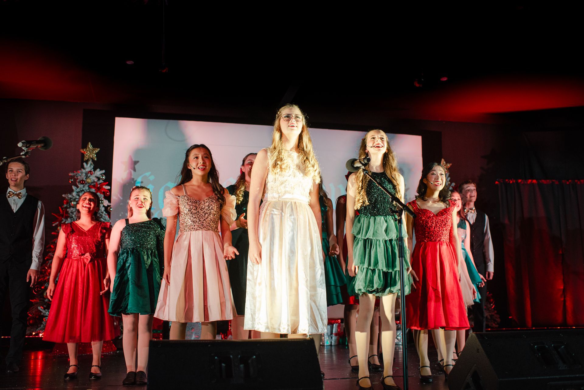 Children in festive dresses standing on a stage during a holiday performance