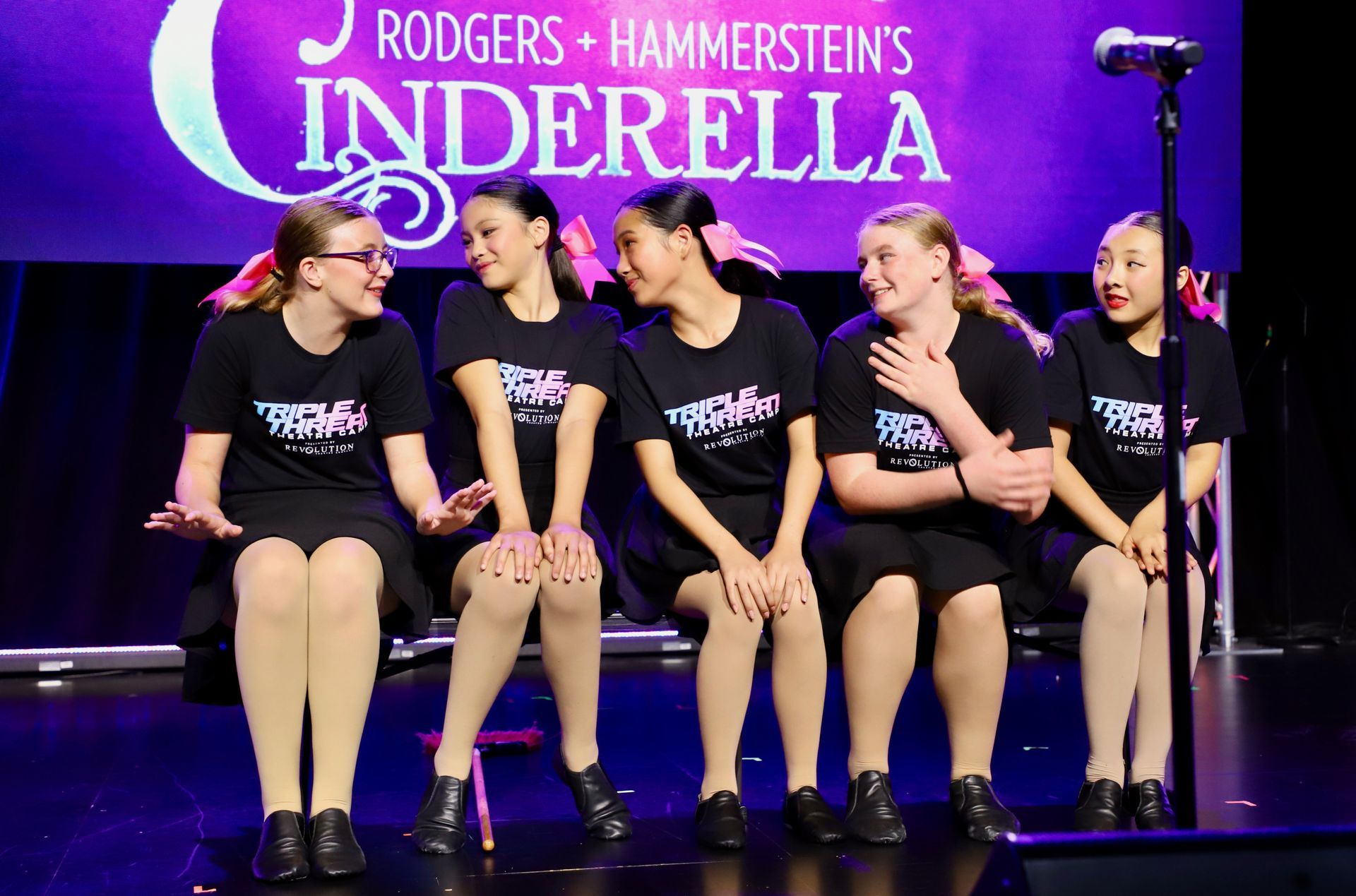 Five performers on stage beneath a purple Rodgers & Hammerstein's Cinderella backdrop for a theater showcase.