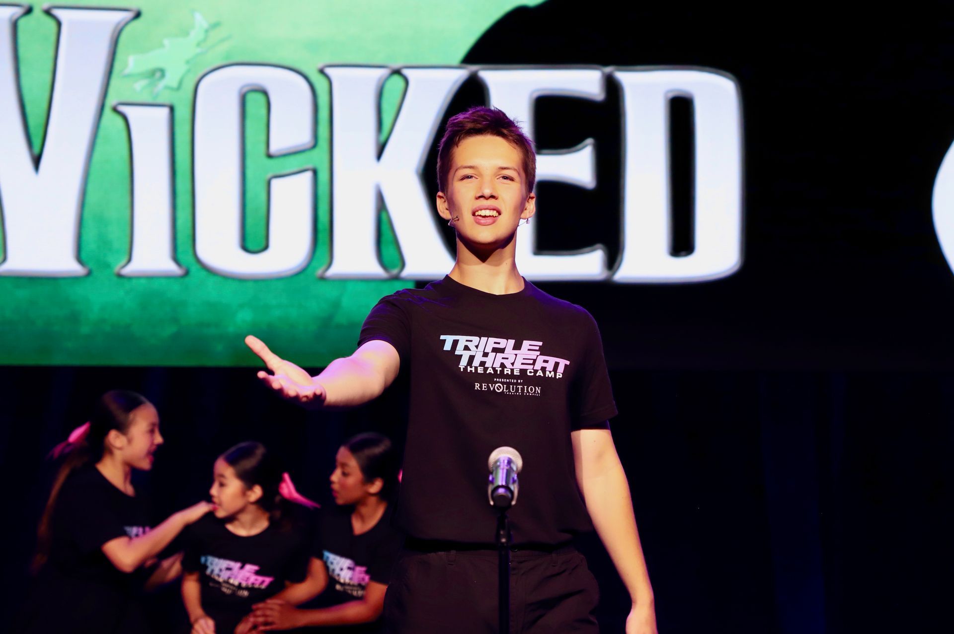 Person onstage singing in front of a large 