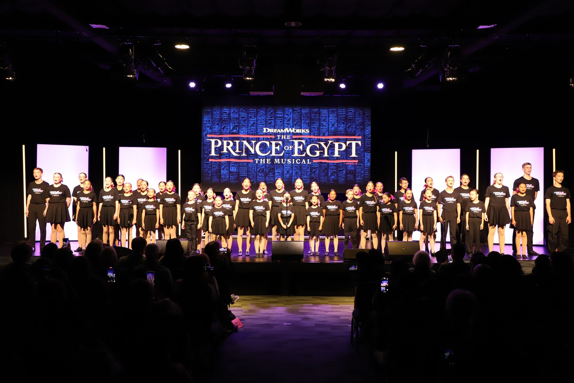 Large group on a lit stage with a “Fonce fait” banner for a theater showcase.