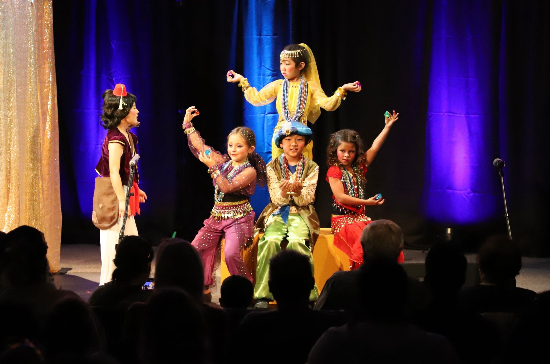 A group of young girls are dancing on a stage in front of a crowd.