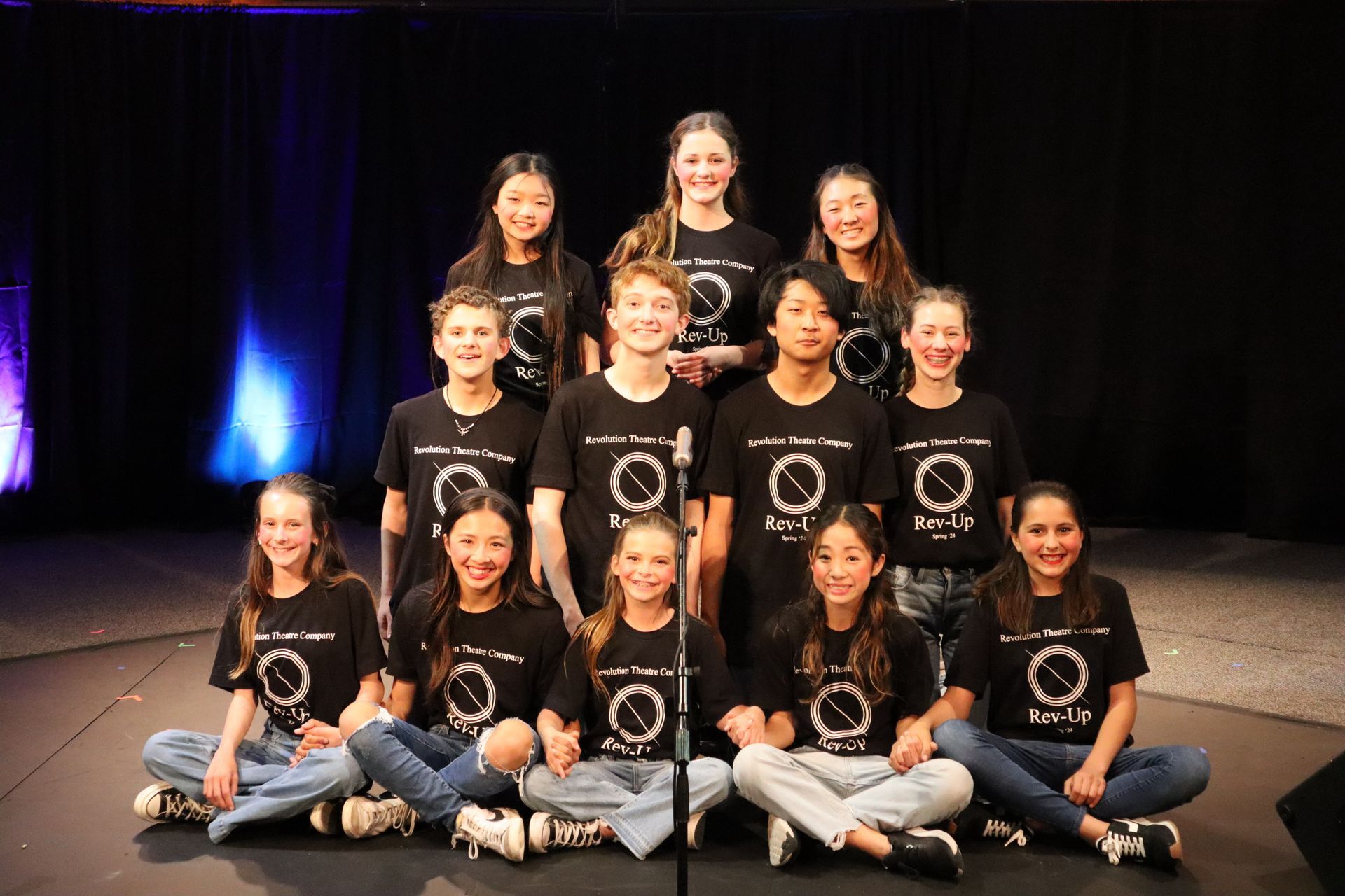 A group of young people are posing for a picture on a stage.