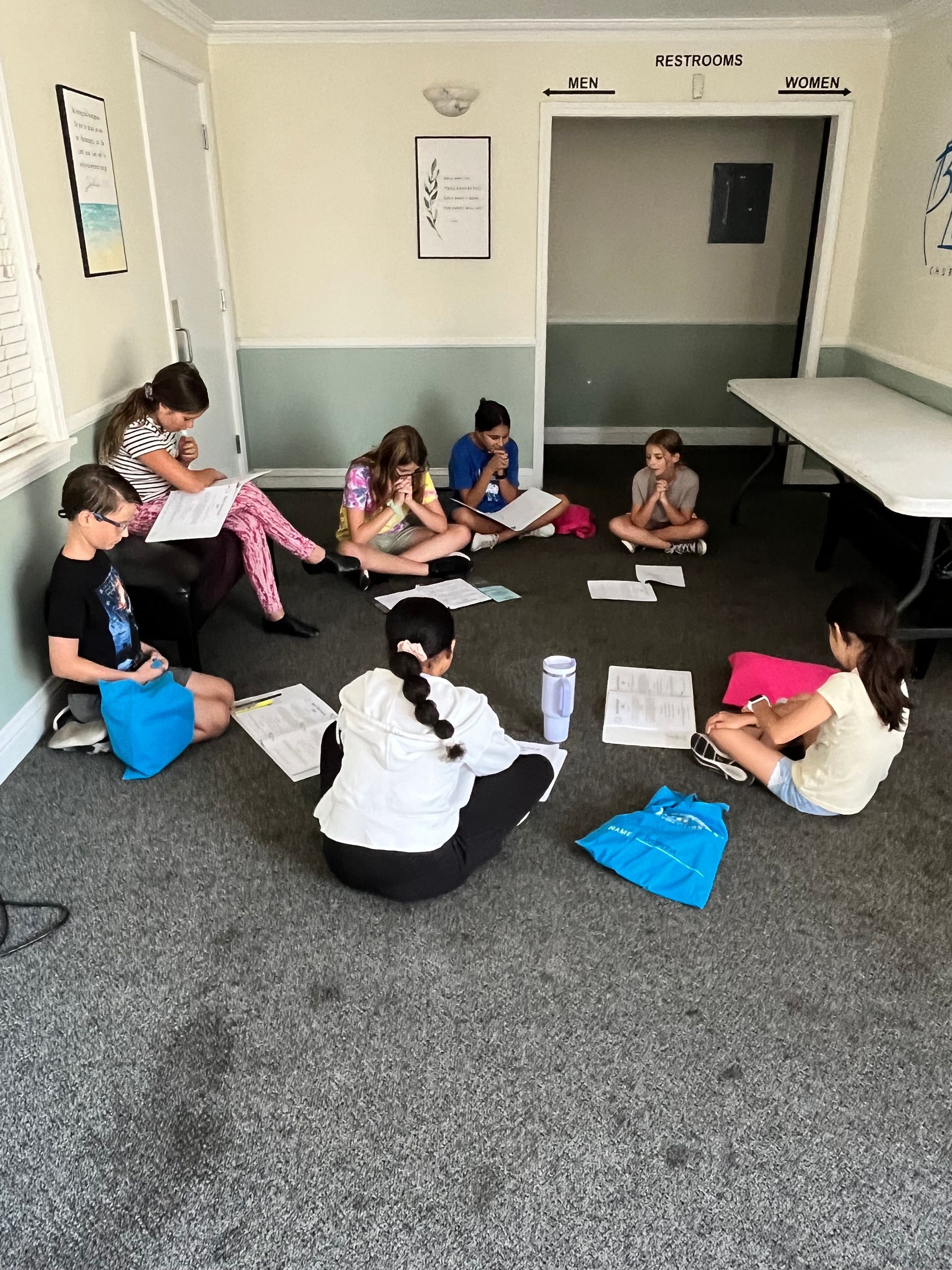 A group of children are sitting in a circle on the floor reading books.
