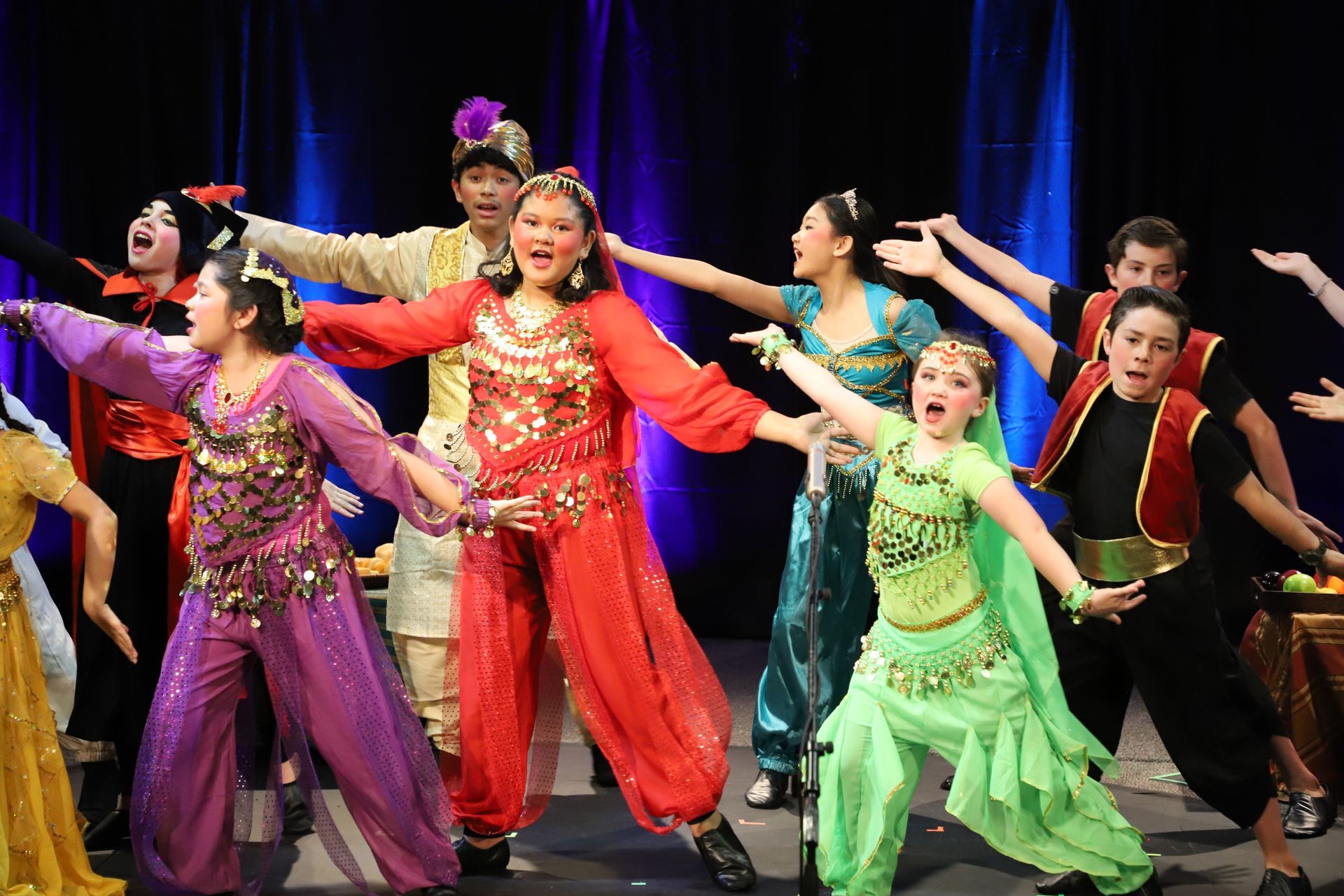 A group of children in costume are dancing on a stage.