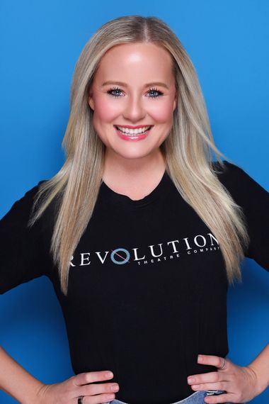 A woman with blonde hair and blue eyes is wearing a purple top
