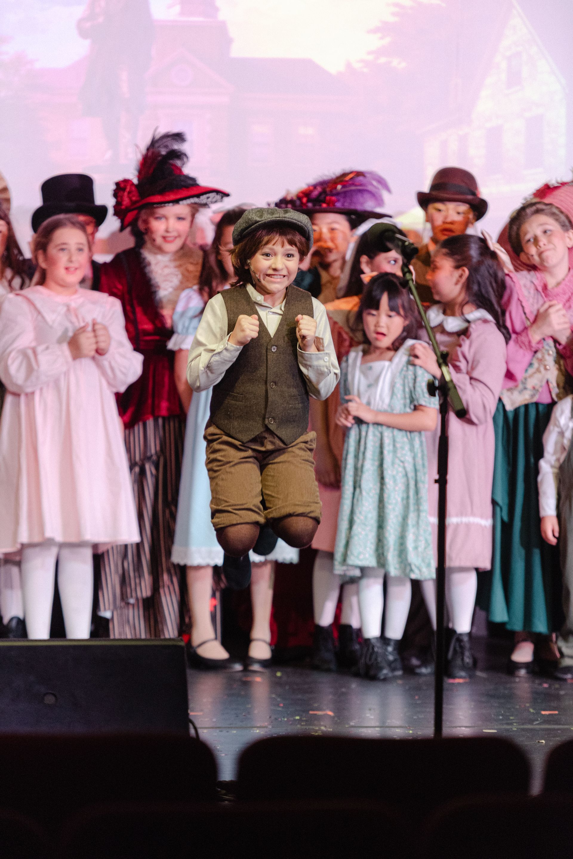 Children in period costumes performing on stage under pink lighting from The Music Man