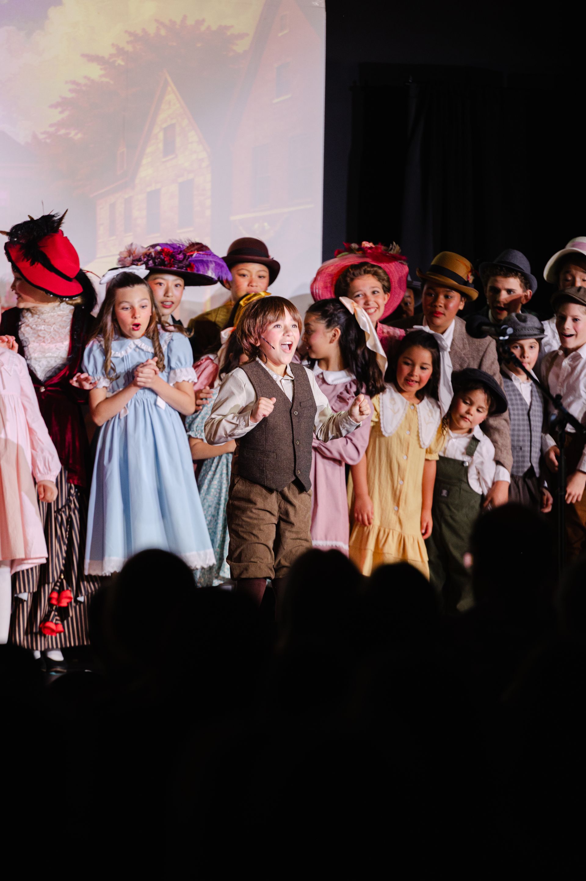 Children in colorful costumes standing onstage during a performance from The Music Man