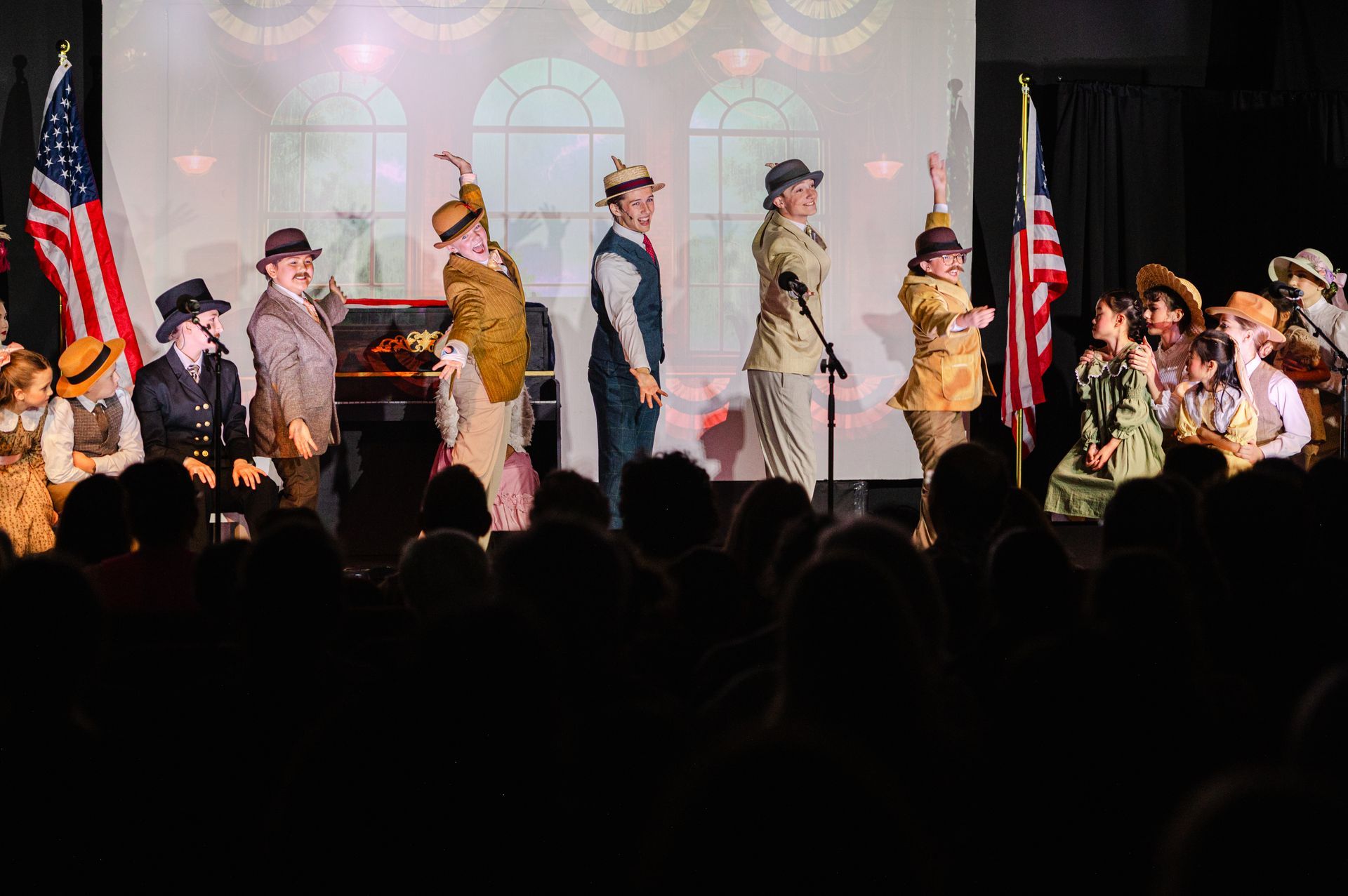 Stage performers in vintage military-style uniforms march under pink lighting before an audience from The Music Man