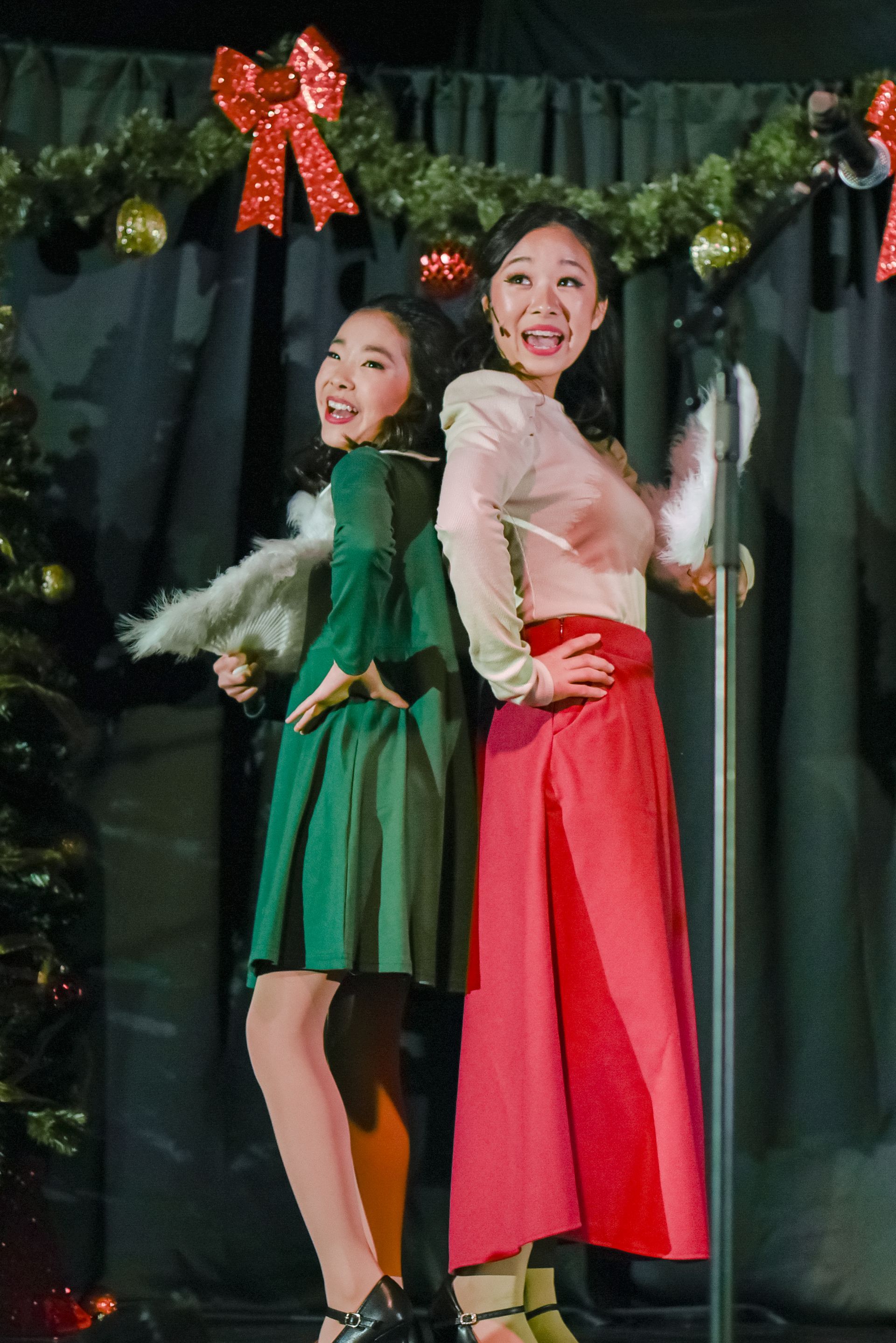 Two performers posing back-to-back on a decorated stage, wearing green and red outfits.