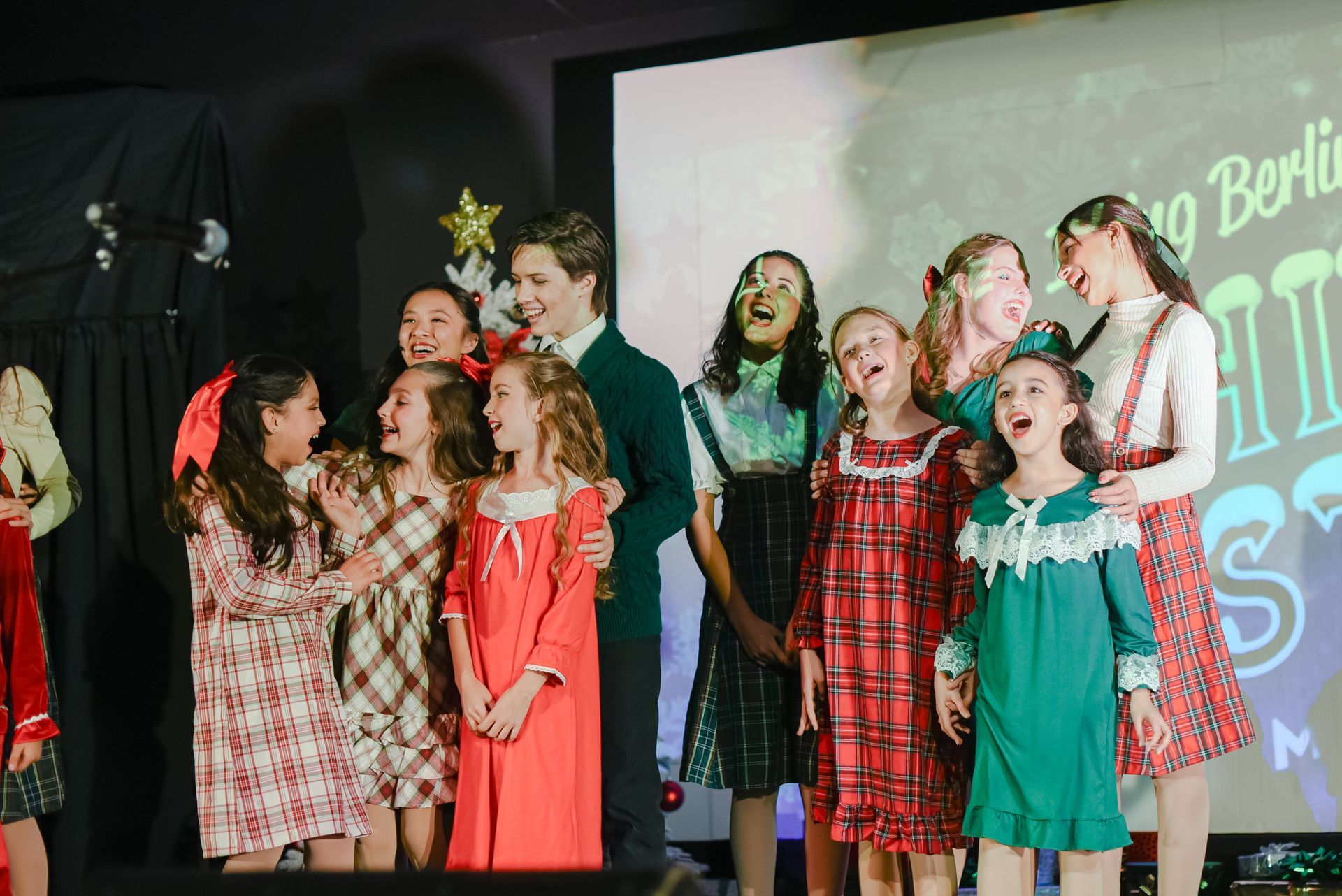 Children singing on stage in colorful dresses during a performance