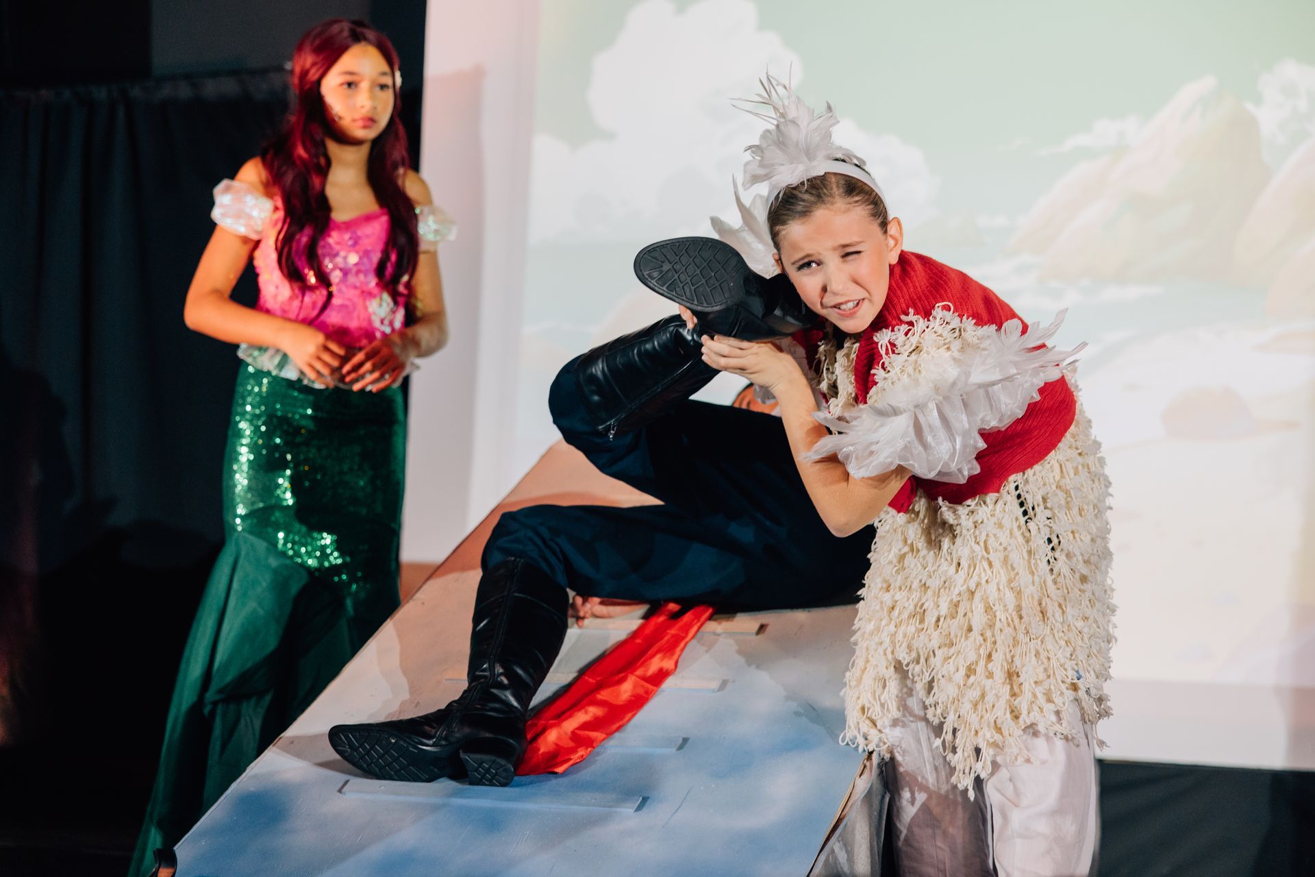 Two children in colorful costumes posing on a stage-like set for the Little Mermaid stage production.