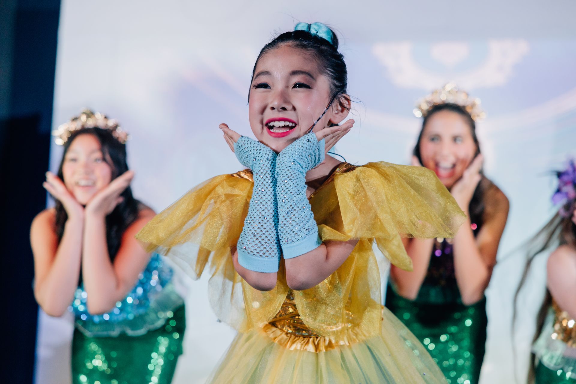 Three dancers in colorful costumes posing and smiling on stage for the Little Mermaid stage production.