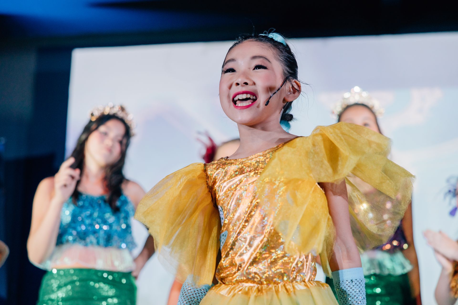 Children performing a dance on stage in colorful costumes for the Little Mermaid stage production.