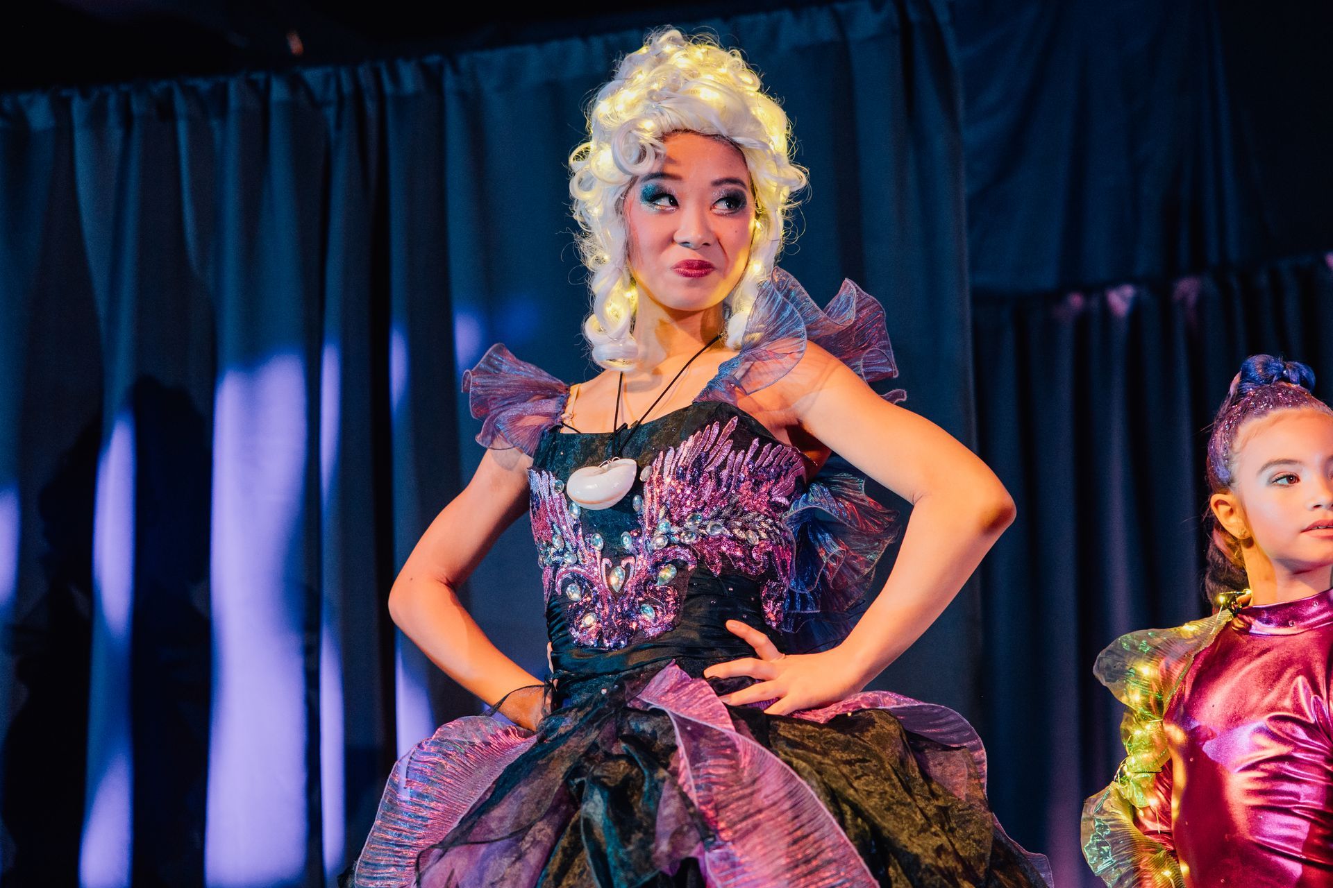 Two performers in colorful costumes onstage for the Little Mermaid stage production.
