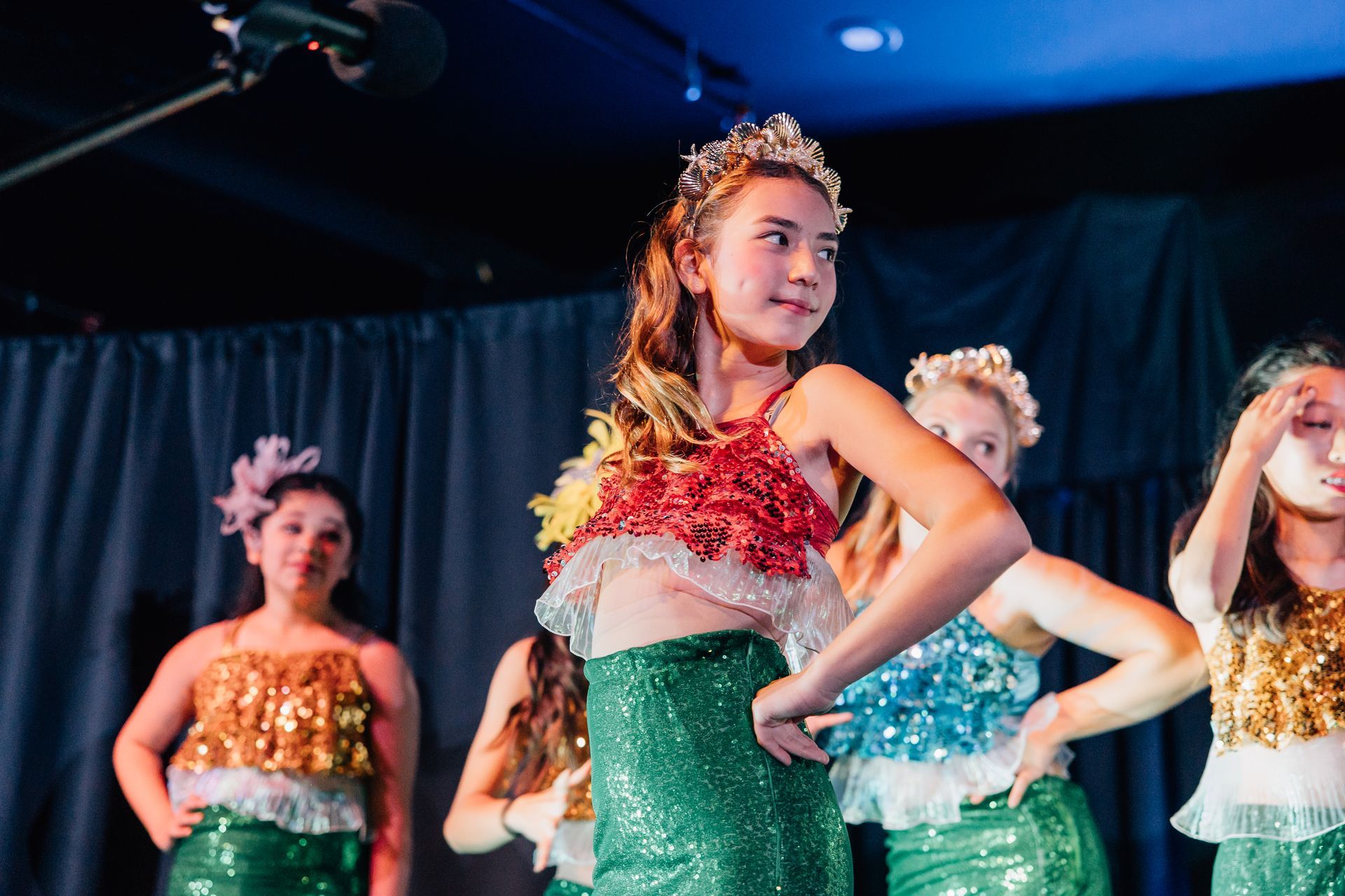 Dancers in sparkly costumes performing onstage under blue and purple lights. for the  Little Mermaid stage production.