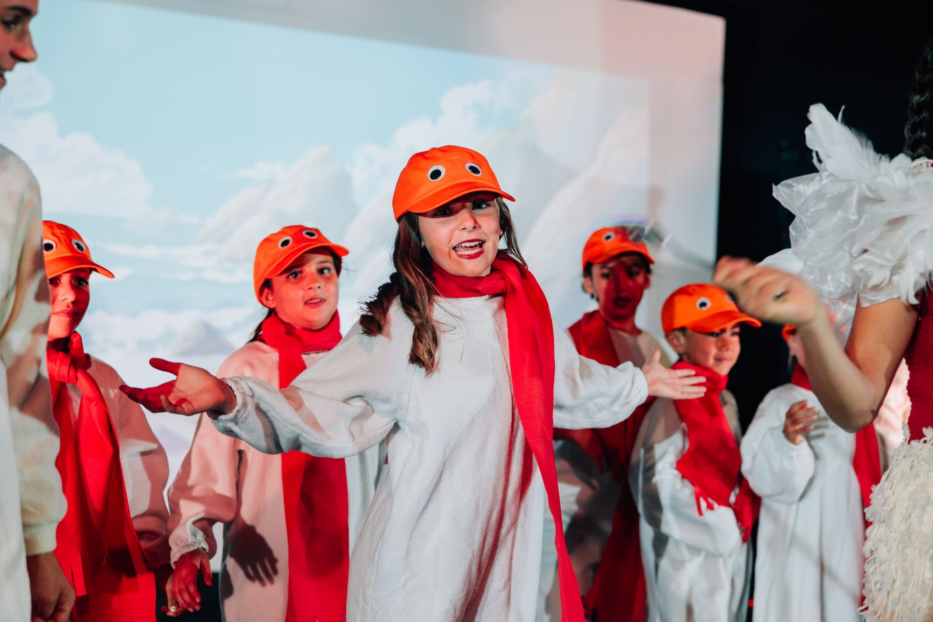 Children in costumes, with red scarves and wing props for the  Little Mermaid stage production.