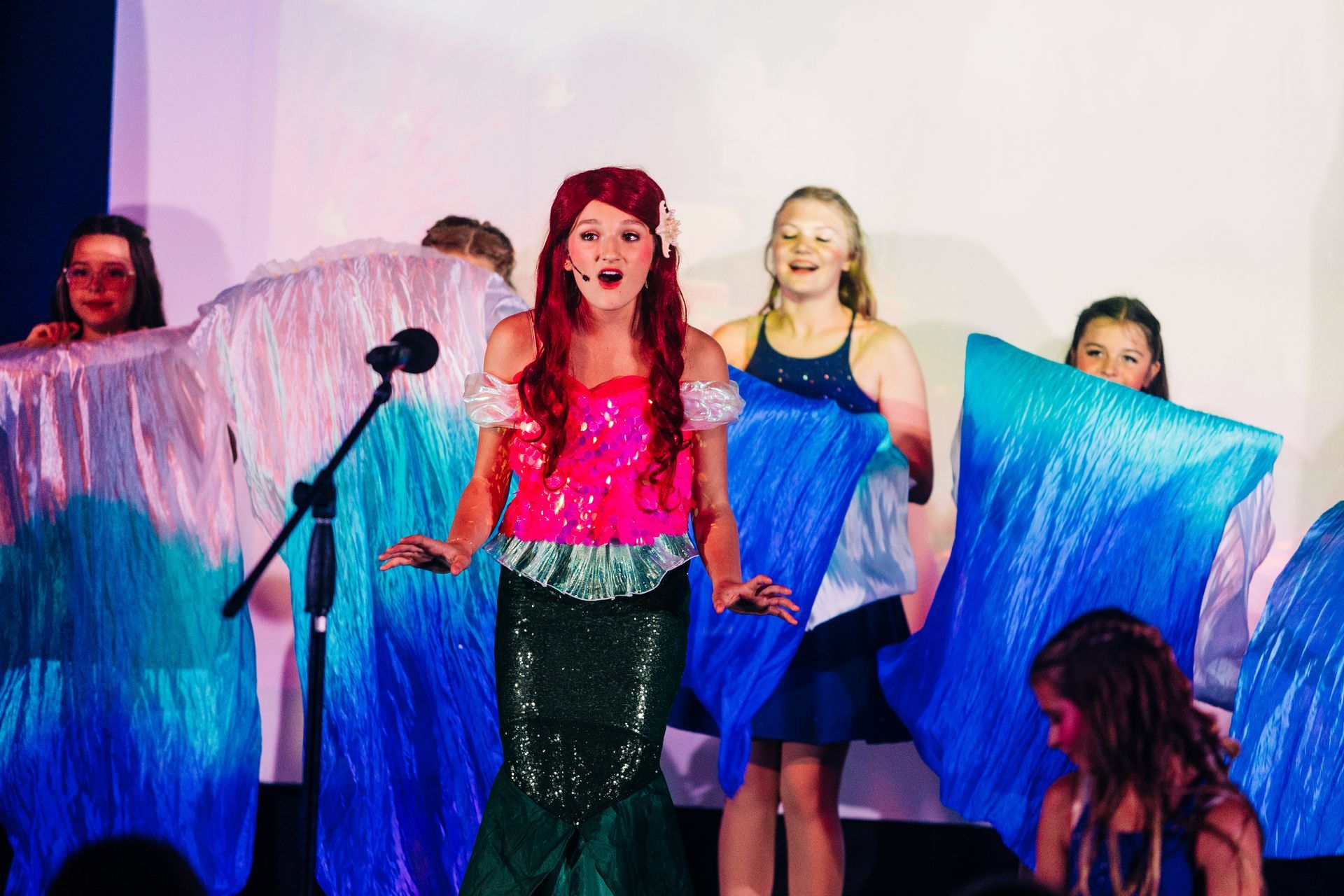 Youth theater performers in sequin mermaid costumes during a Little Mermaid stage production at Revolution Theatre Company.