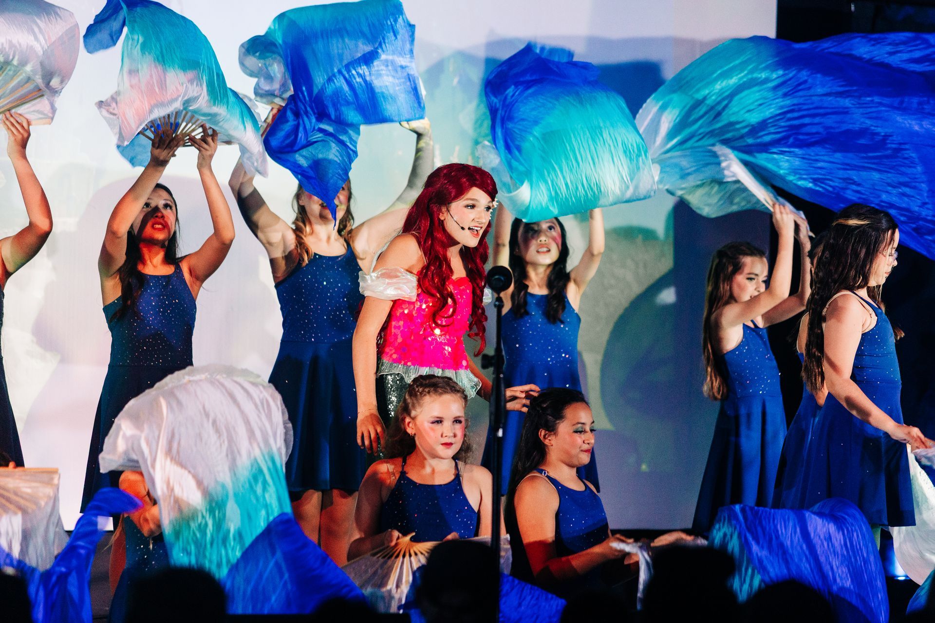 Youth theater performers in sequin mermaid costumes during a Little Mermaid stage production at Revolution Theatre Company.