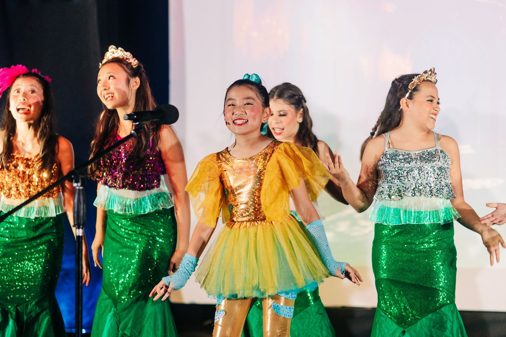 Four dancers in colorful costumes performing on stage under bright lights