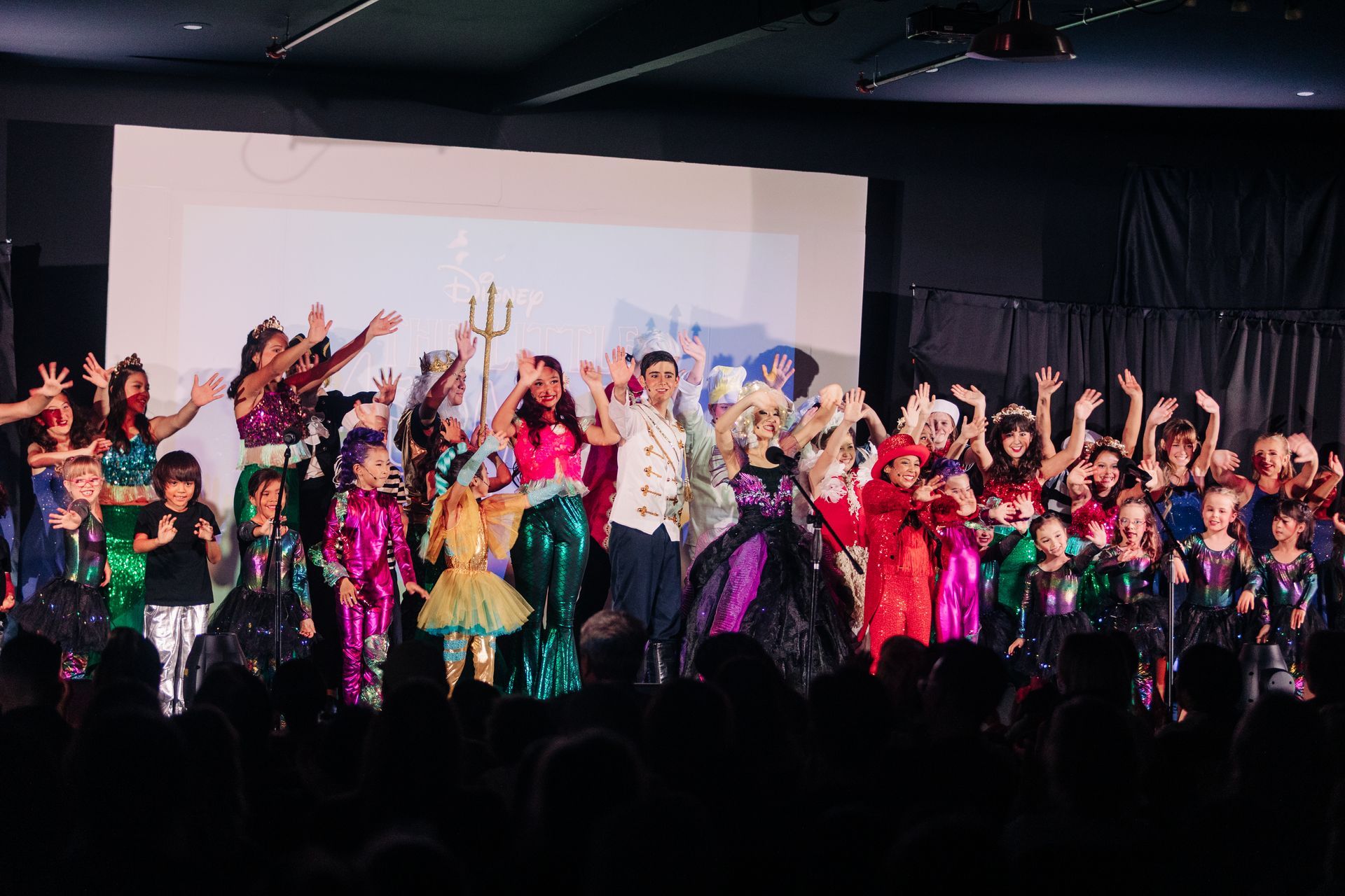 Costumed dancers on a stage with raised arms during a colorful performance
