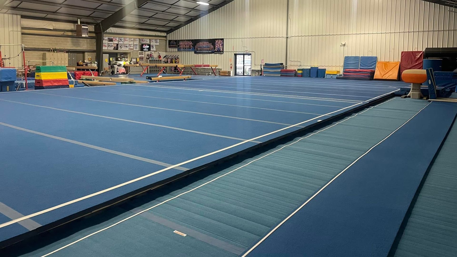 A large indoor gym with a blue floor and a lot of equipment.