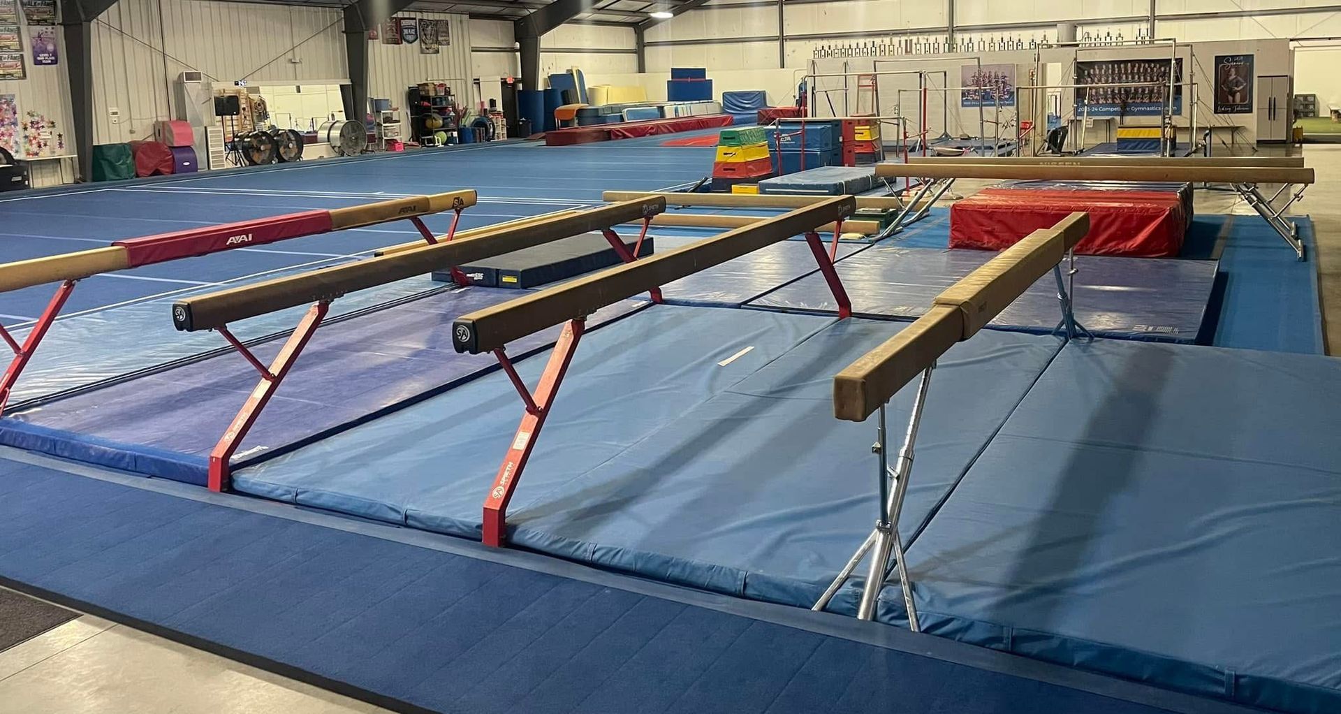 A row of balance beam in a gym with a blue mat.