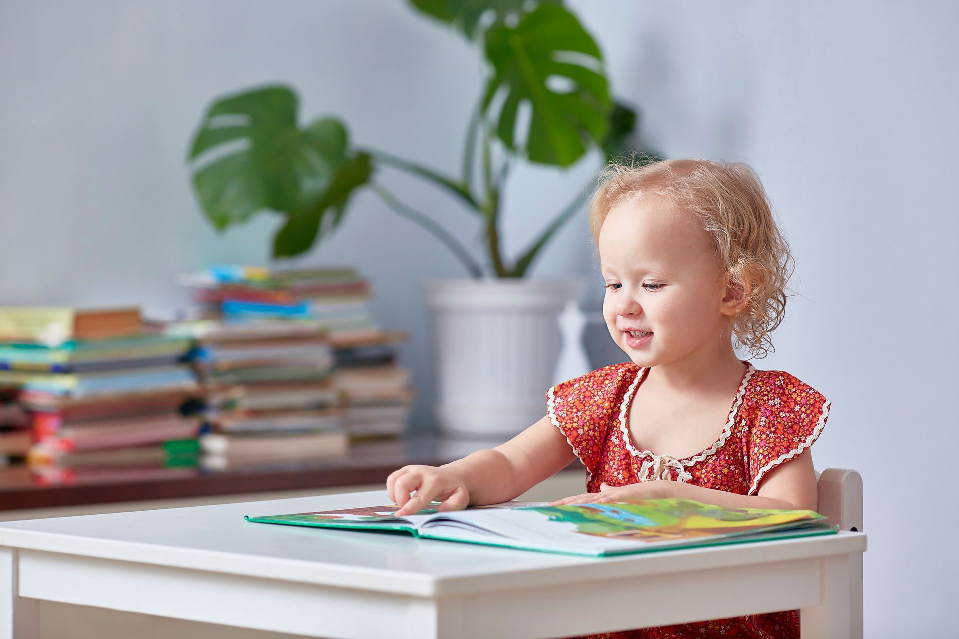 Una bambina è seduta a un tavolo e legge un libro.
