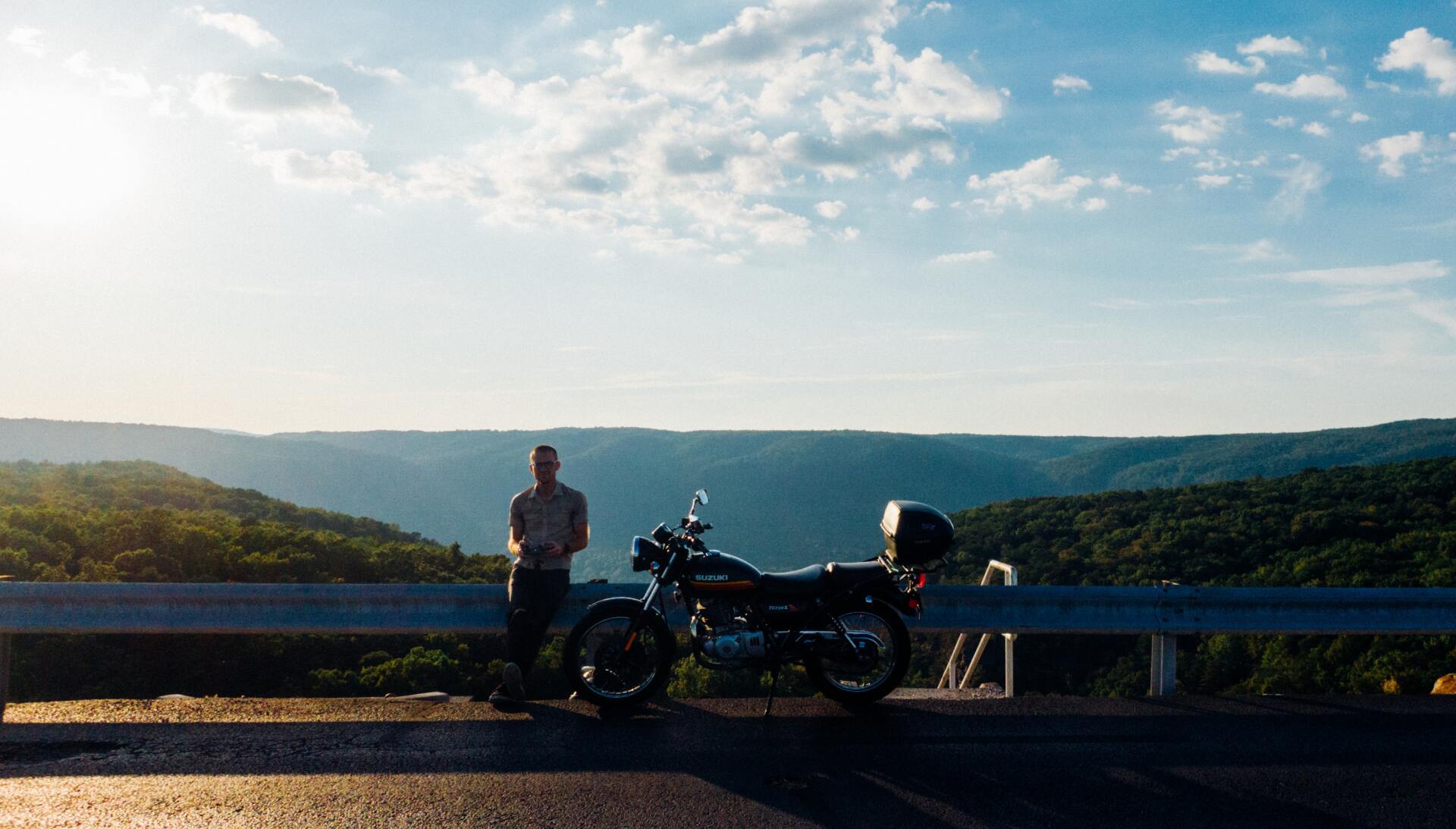man leaning on metal frame beside motorcycle