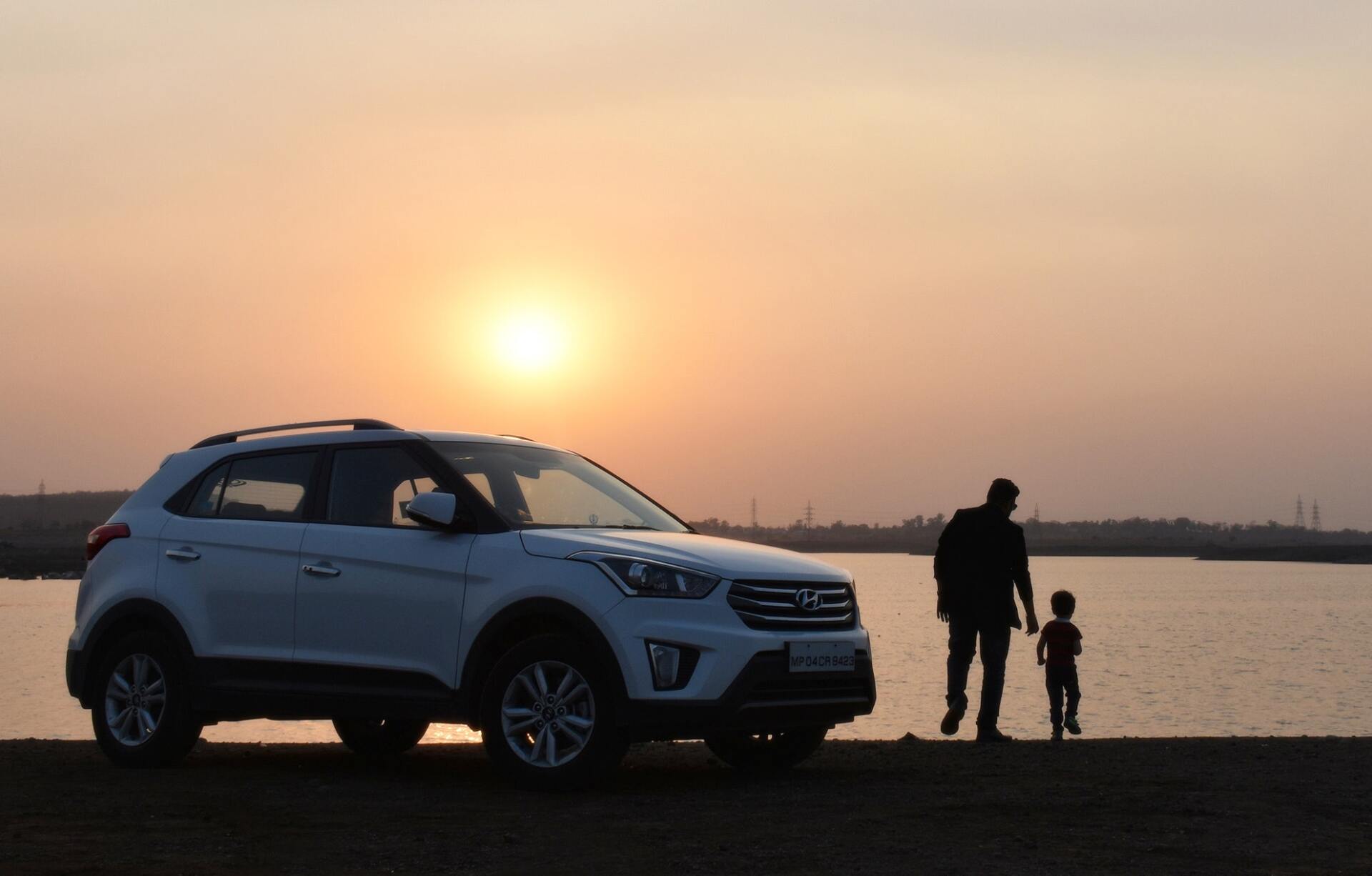silhouette of man and child near white suv