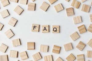 The letters F, A, and Q on wooden tiles centered among many scattered, blank wooden tiles on a white background.