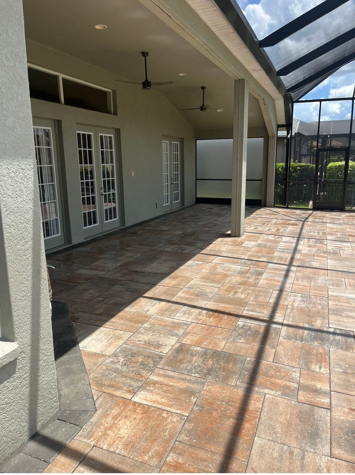 A large covered patio with a ceiling fan and sliding glass doors.
